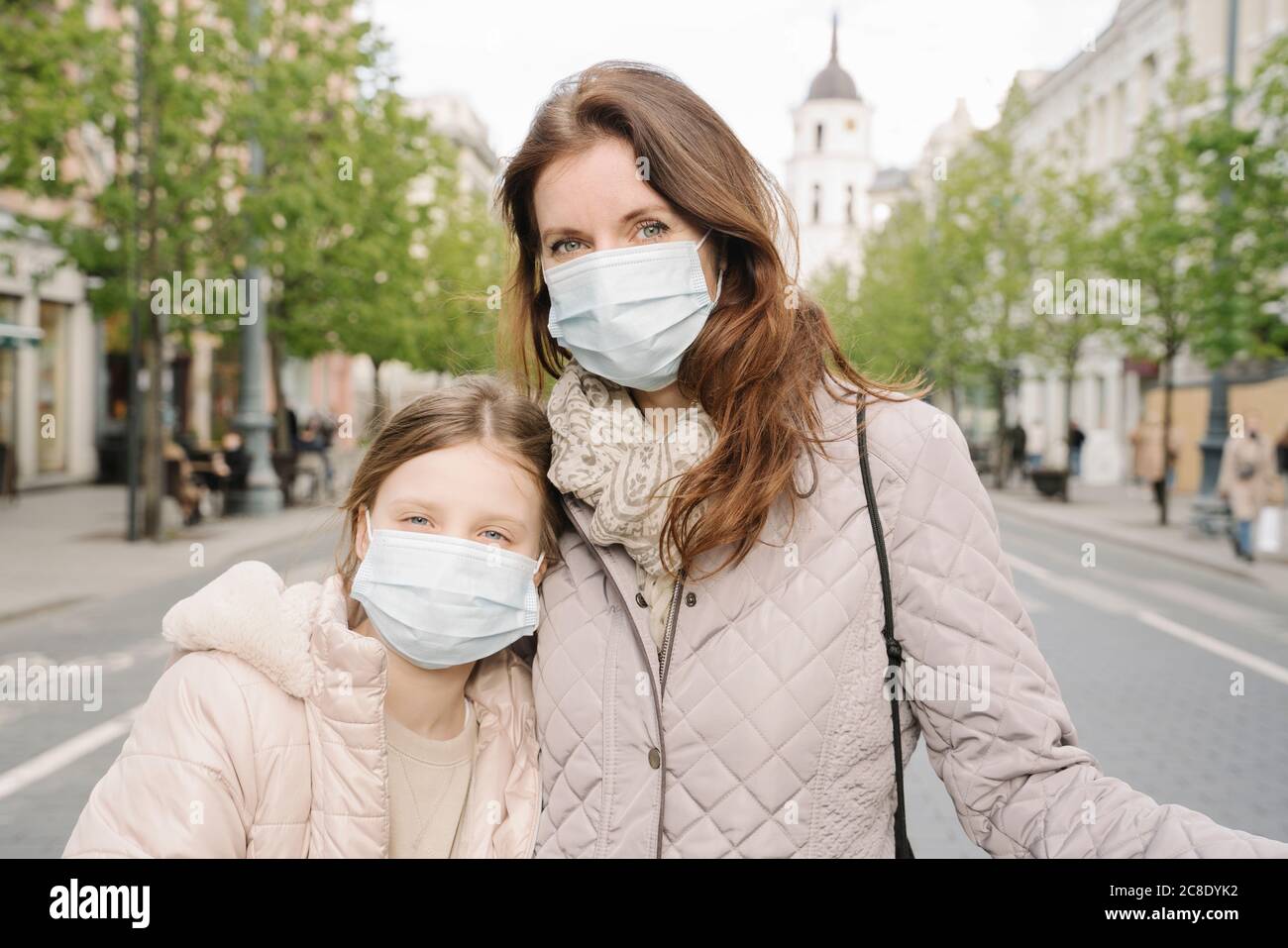 Madre e figlia indossano maschere in piedi sulla strada in città Foto Stock