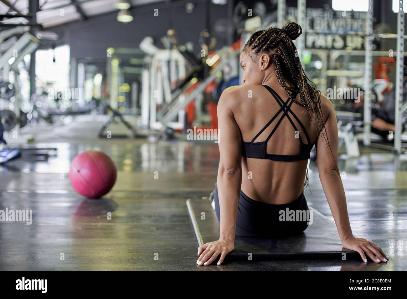 Atleta femminile con capelli intrecciati poggiati sul tappetino per esercizi palestra Foto Stock