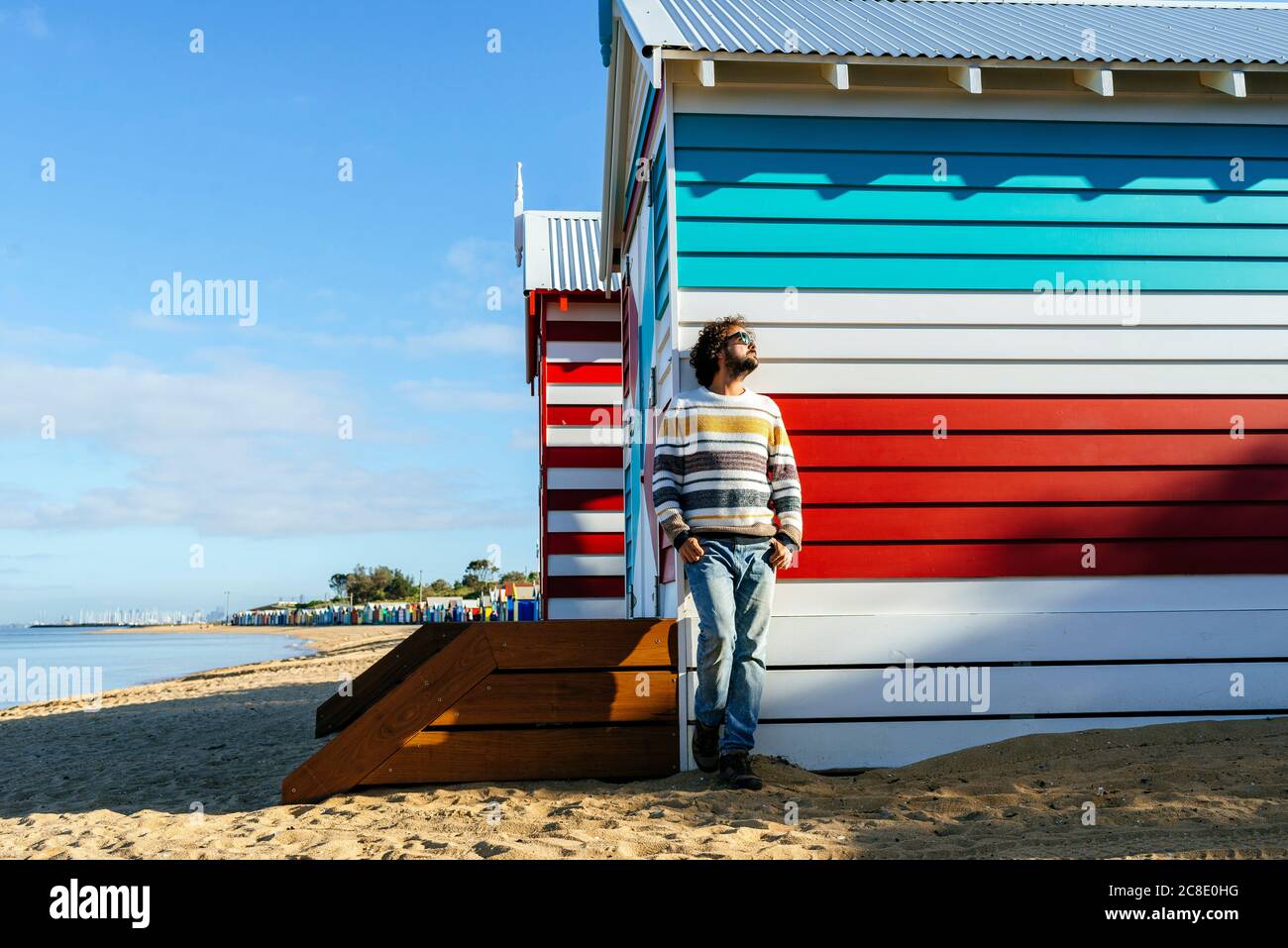 Uomo in piedi da cottage a Brighton Beach, Melbourne, Australia Foto Stock