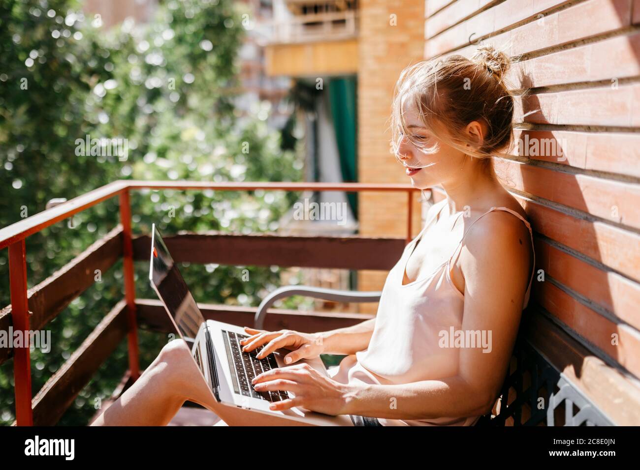 Giovane donna che lavora su un computer portatile in balcone Foto Stock