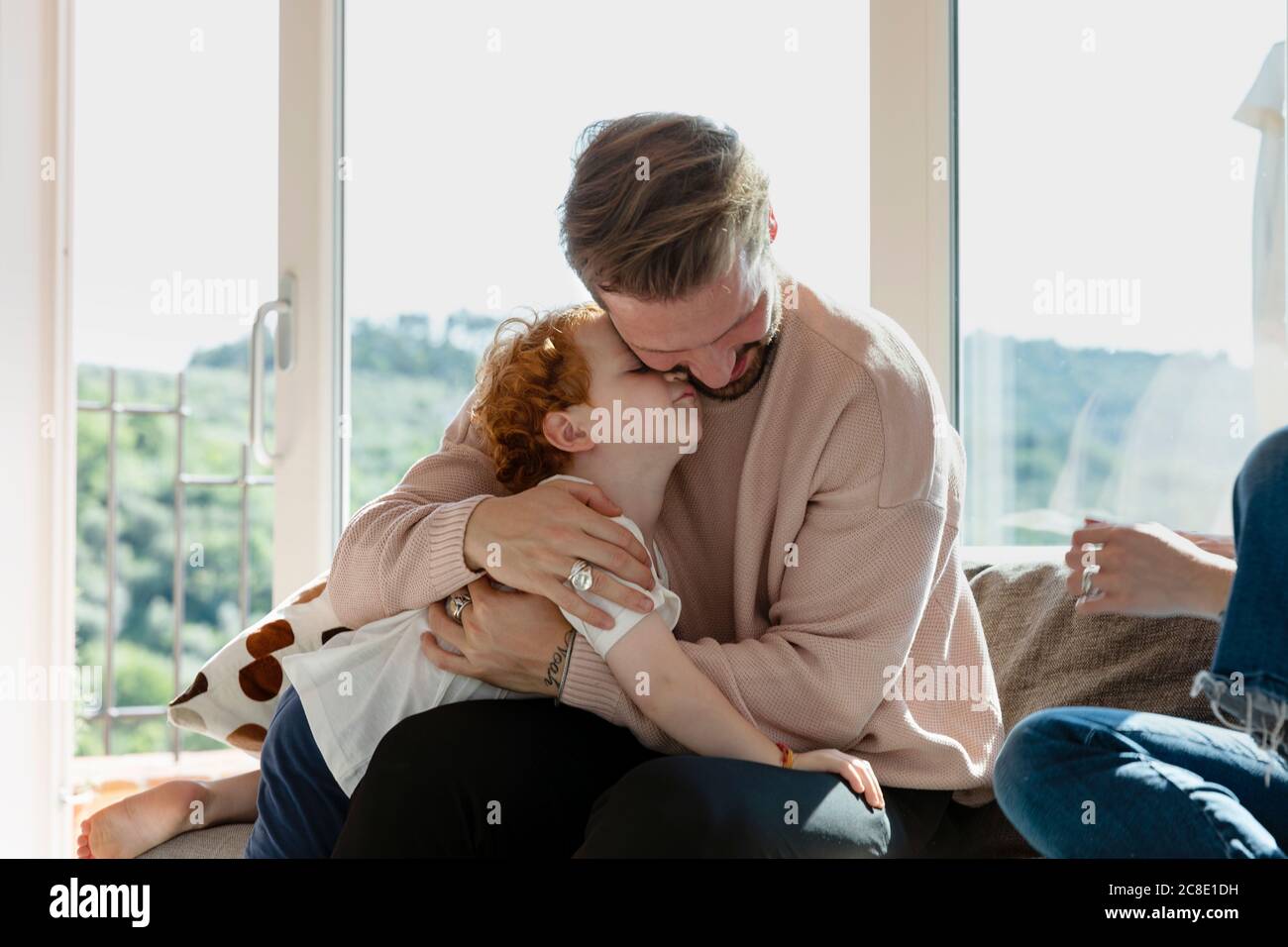 L'uomo abbracciando il figlio carino preschool mentre sedendo dalla donna dentro soggiorno a casa Foto Stock