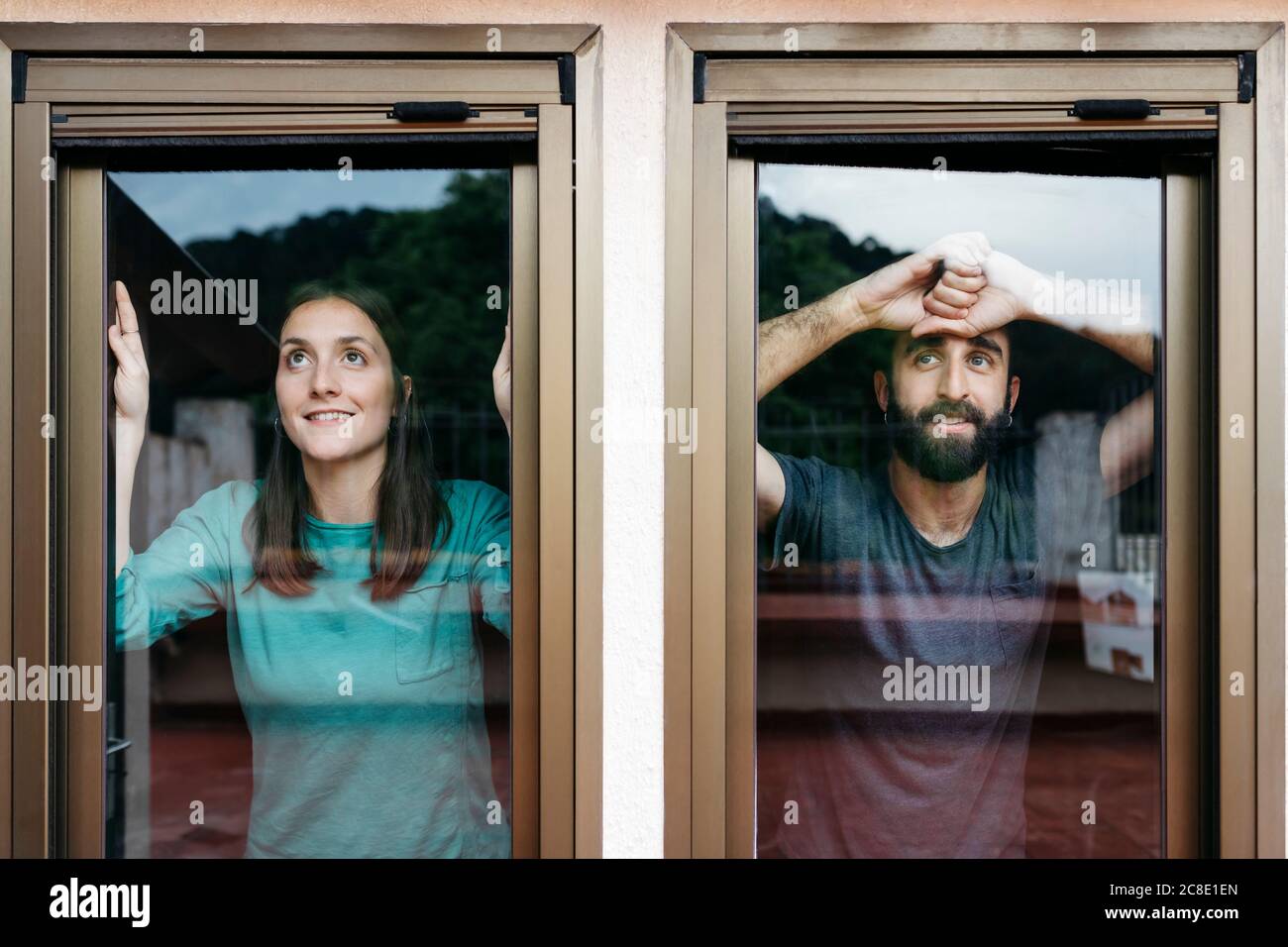 Coppia guardando fuori la finestra e pensando al futuro Foto Stock
