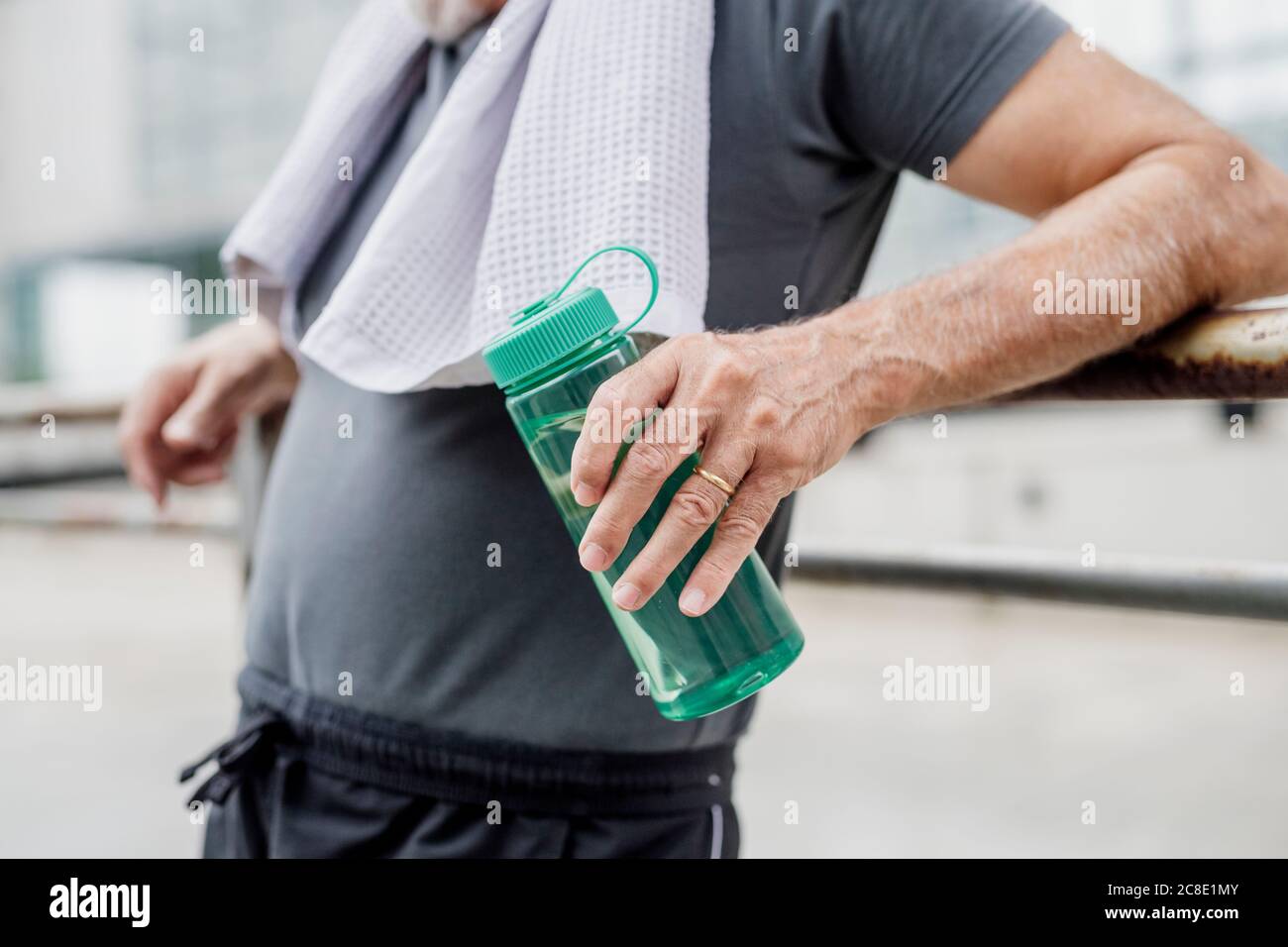 Primo piano di un uomo anziano che tiene una bottiglia d'acqua mentre si è in piedi città Foto Stock