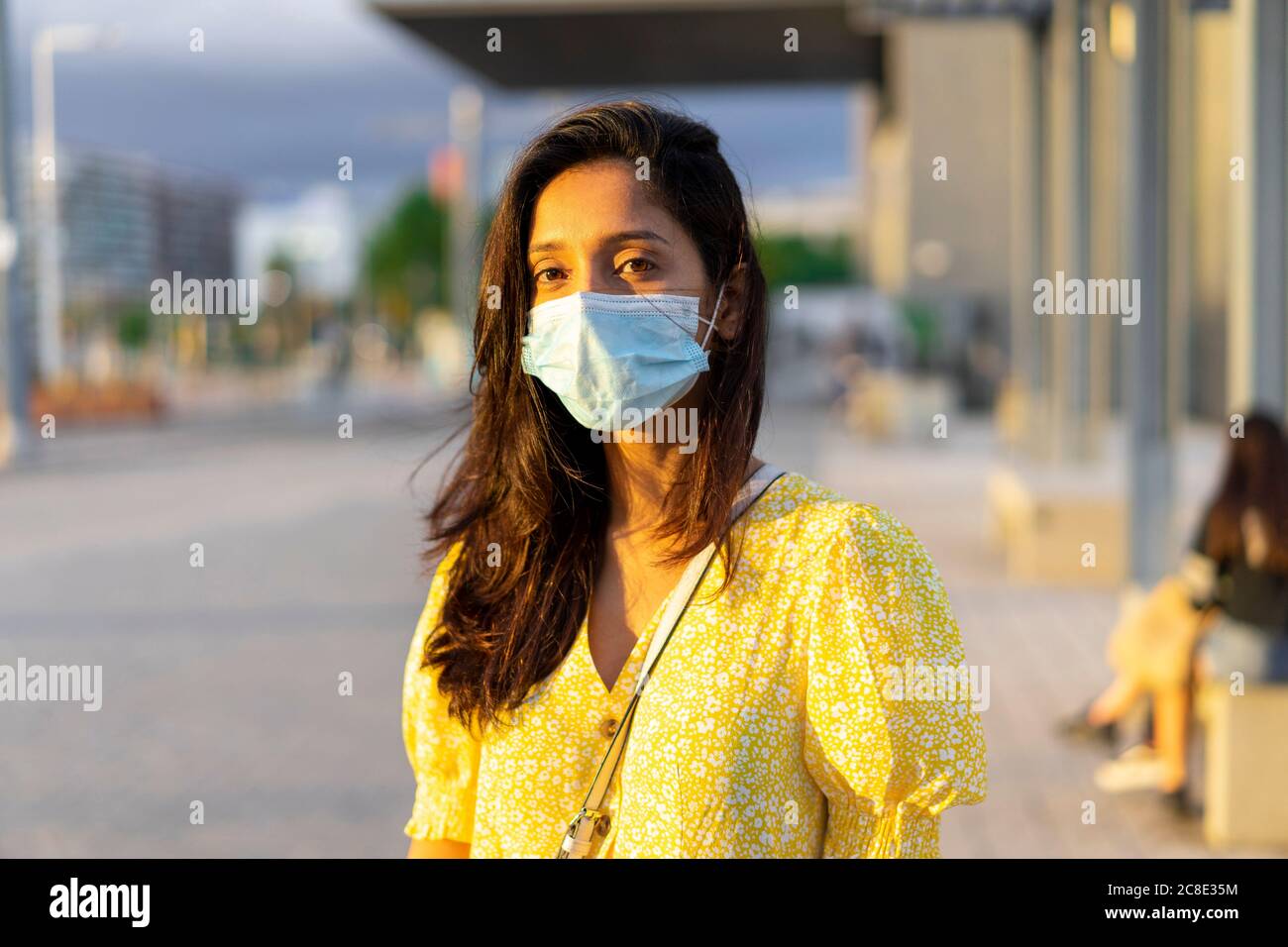 Giovane donna che indossa la maschera mentre si sta in piedi sulla strada della città Foto Stock