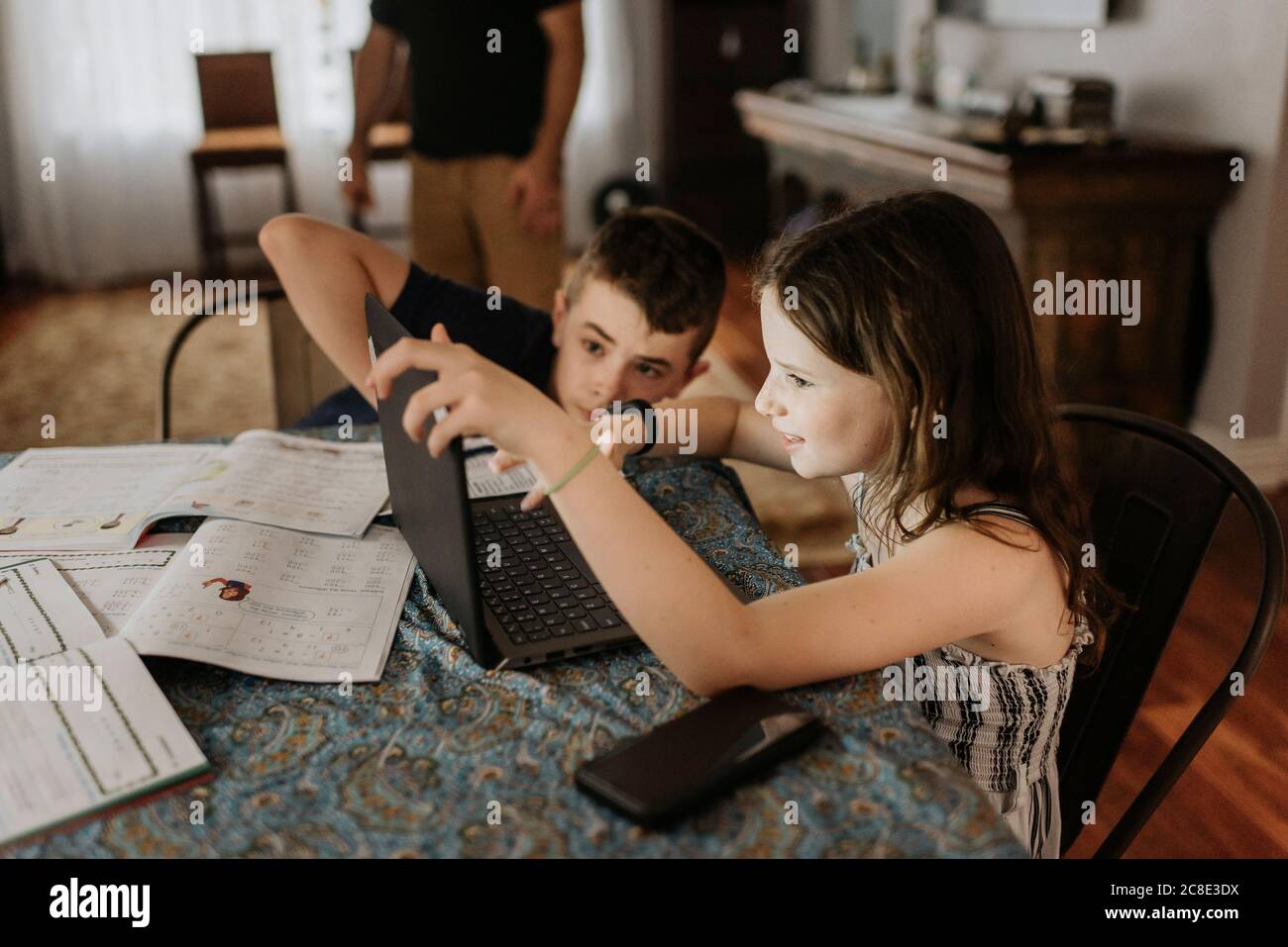 Fratelli che studiano sul laptop a casa durante il coprifuoco Foto Stock