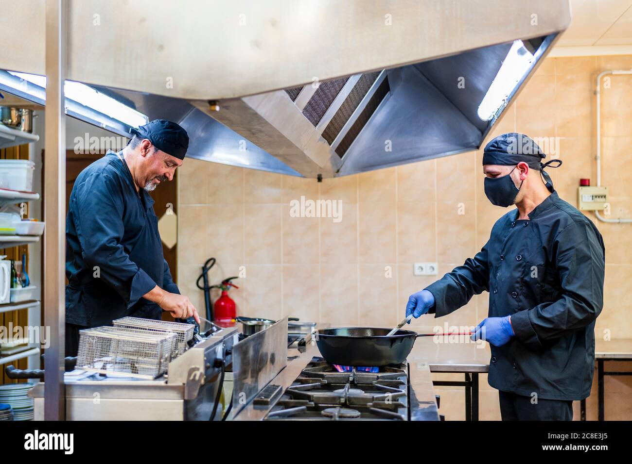 Cucina tradizionale nella cucina del ristorante, chef con maschera protettiva Foto Stock