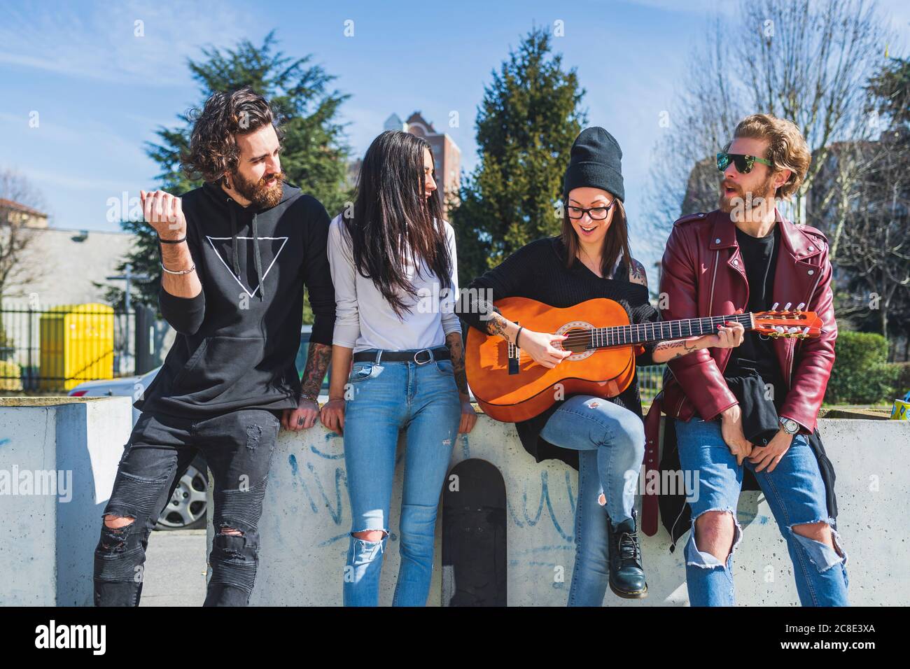 Donna mid adulta che suona la chitarra mentre si diverte con gli amici città Foto Stock