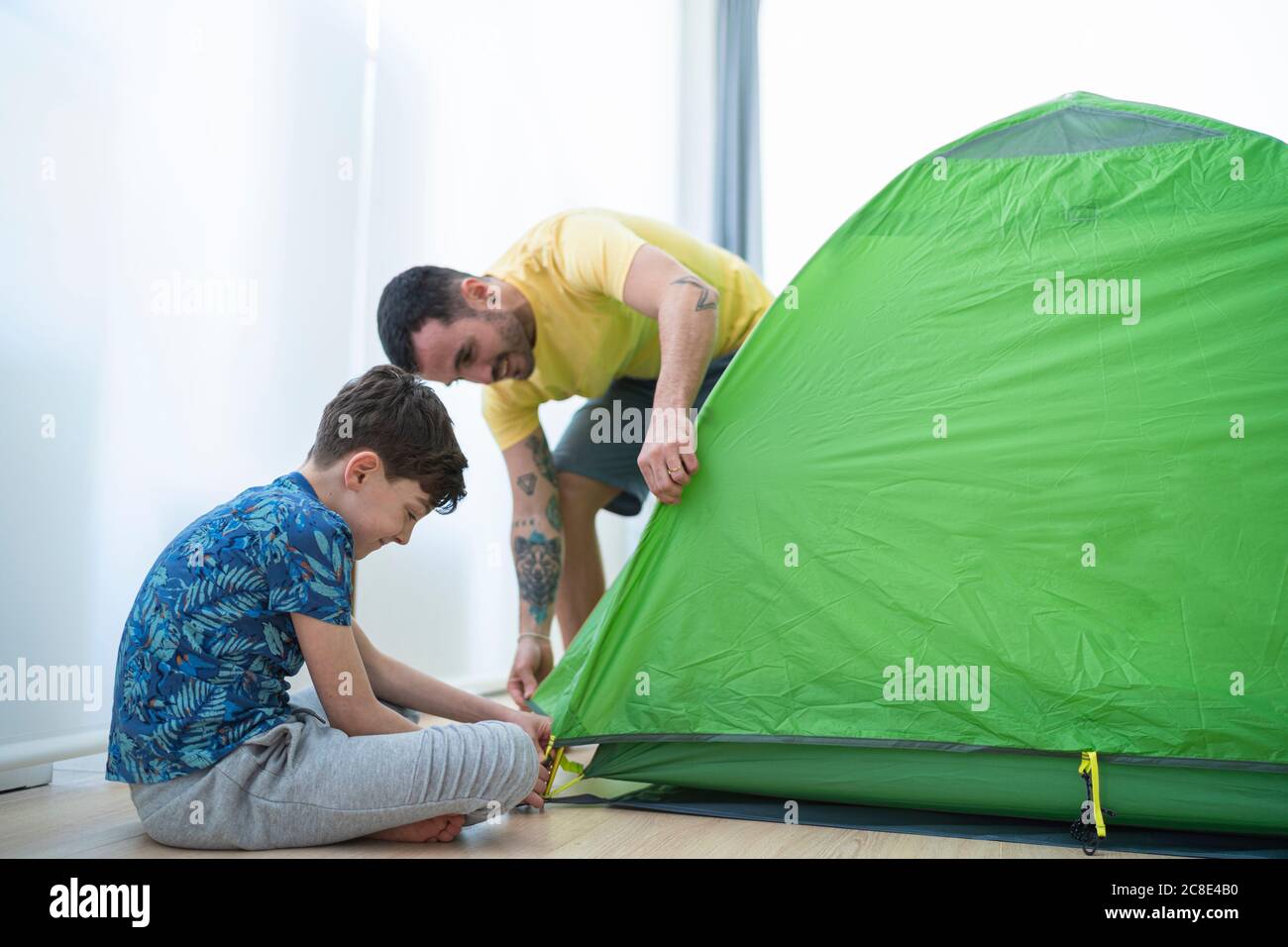 Padre e figlio che mettono la tenda a casa Foto Stock