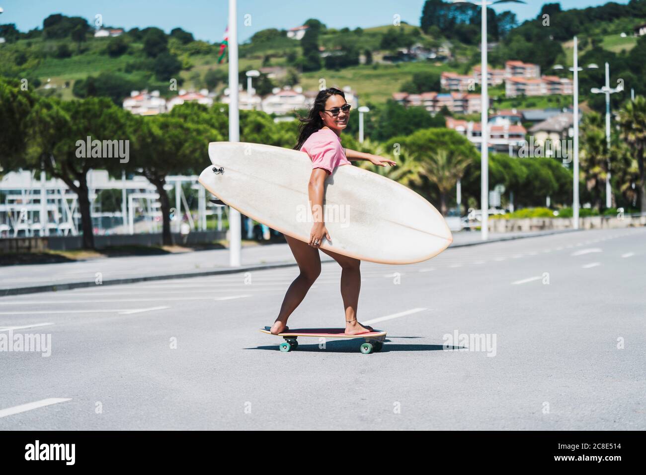 Skateboarder femminile con tavola da surf sulla strada Foto Stock