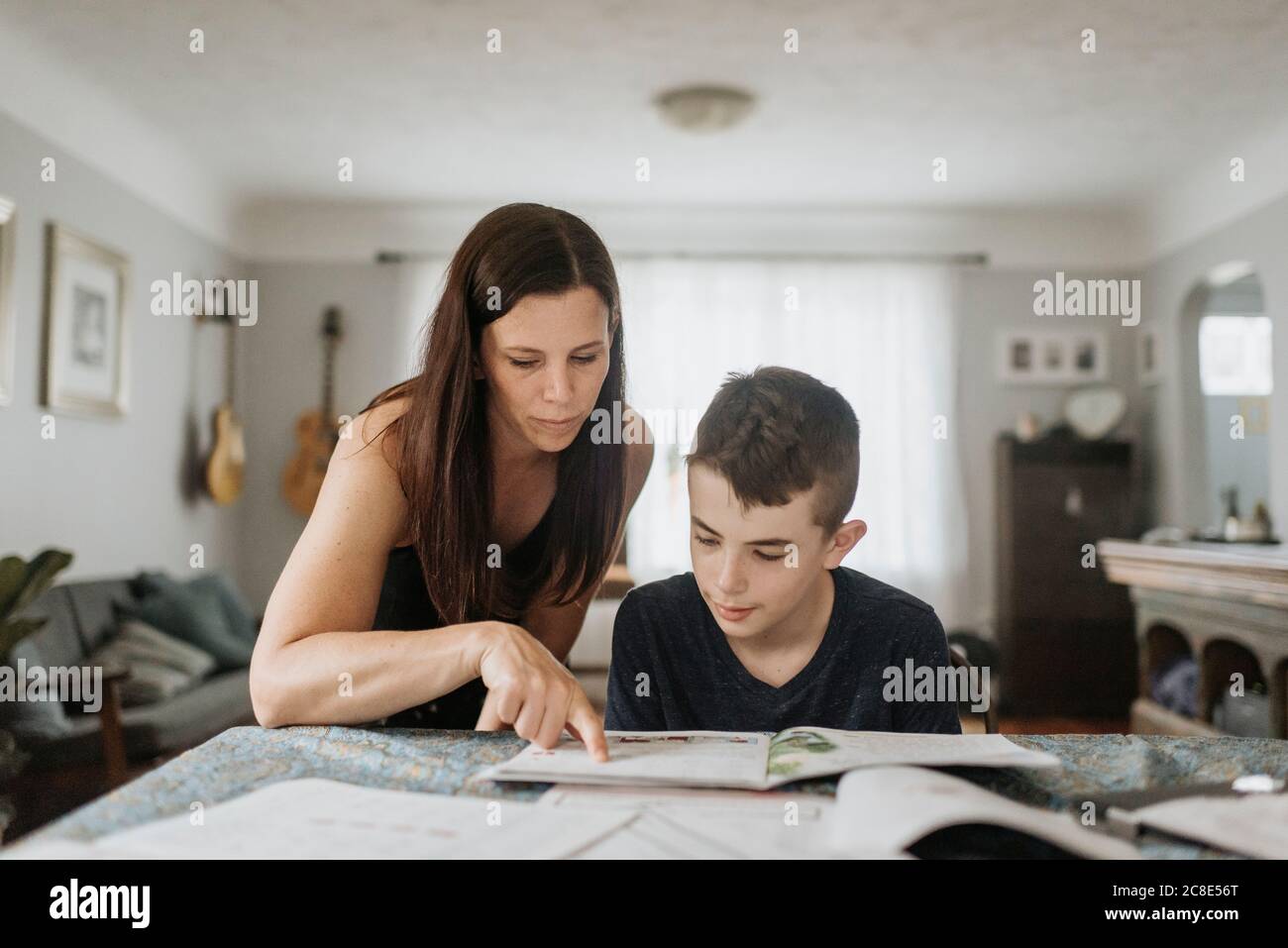 Madre che insegna figlio sul tavolo a casa durante il coprifuoco Foto Stock