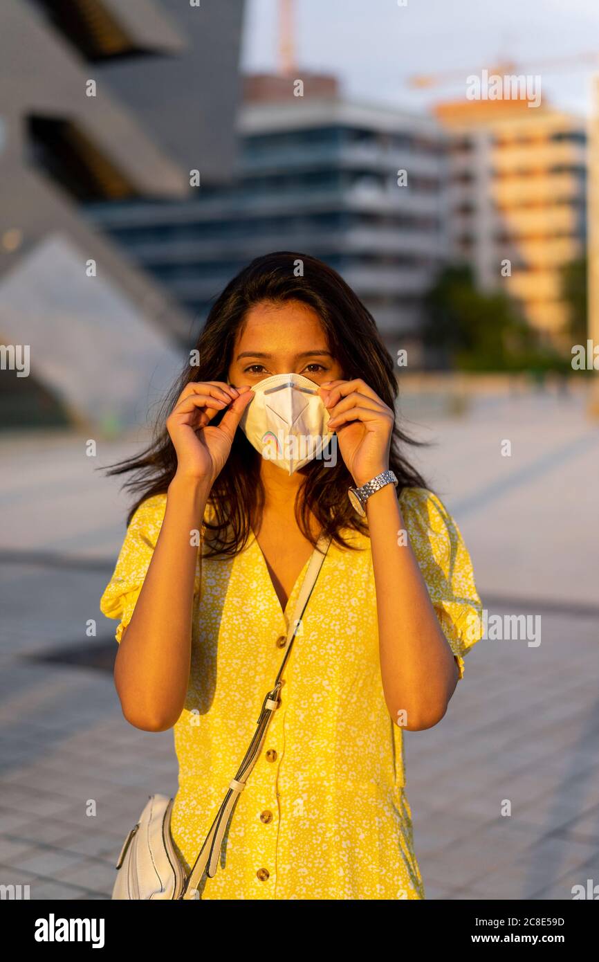 Giovane donna che indossa la maschera mentre si è in piedi in città Foto Stock