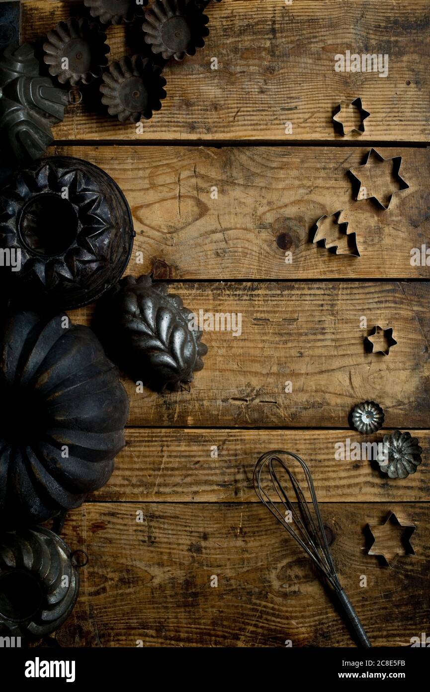 Collezione di vecchi utensili da cucina rustici, tra cui teglie, tagliabiscotti e frusta a filo Foto Stock