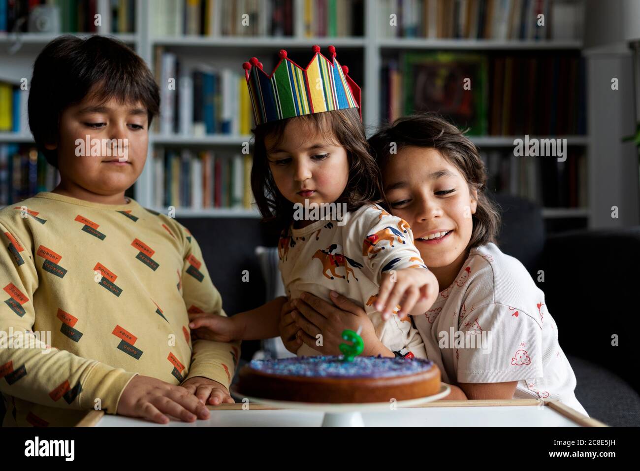 Ritratto di bambina che festeggia il compleanno con i suoi fratelli più anziani a casa Foto Stock