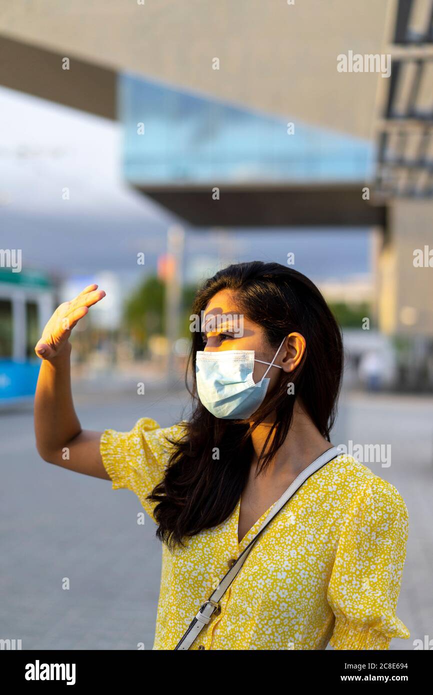 Giovane donna in maschera scherma gli occhi mentre si sta in città via Foto Stock