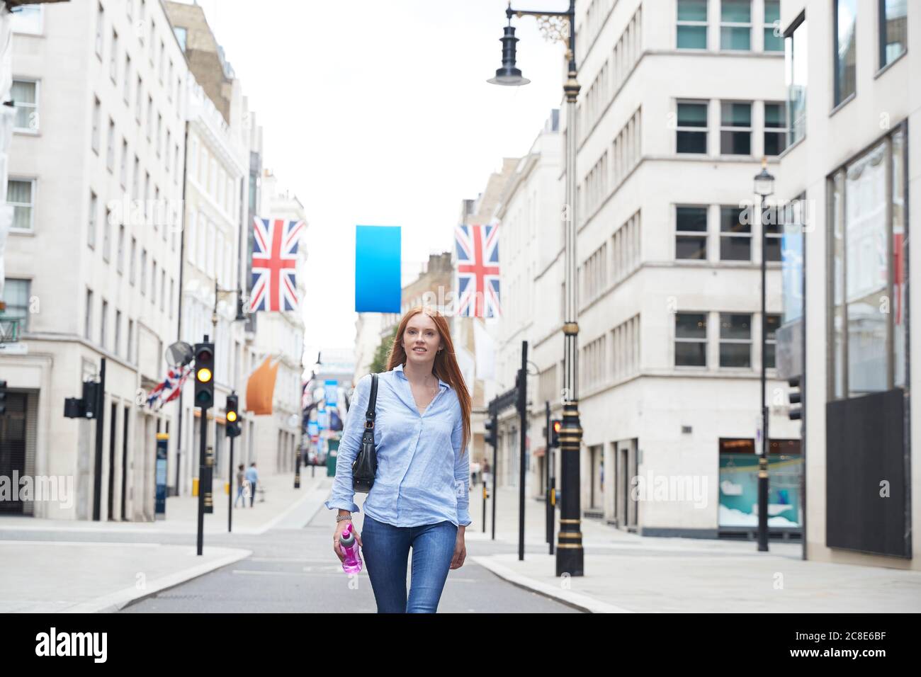 Bella donna rossa che cammina per strada in città Foto Stock