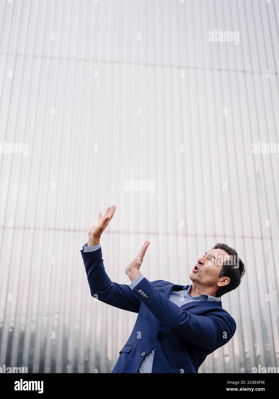 Uomo d'affari maturo ansioso alzando le braccia Foto Stock