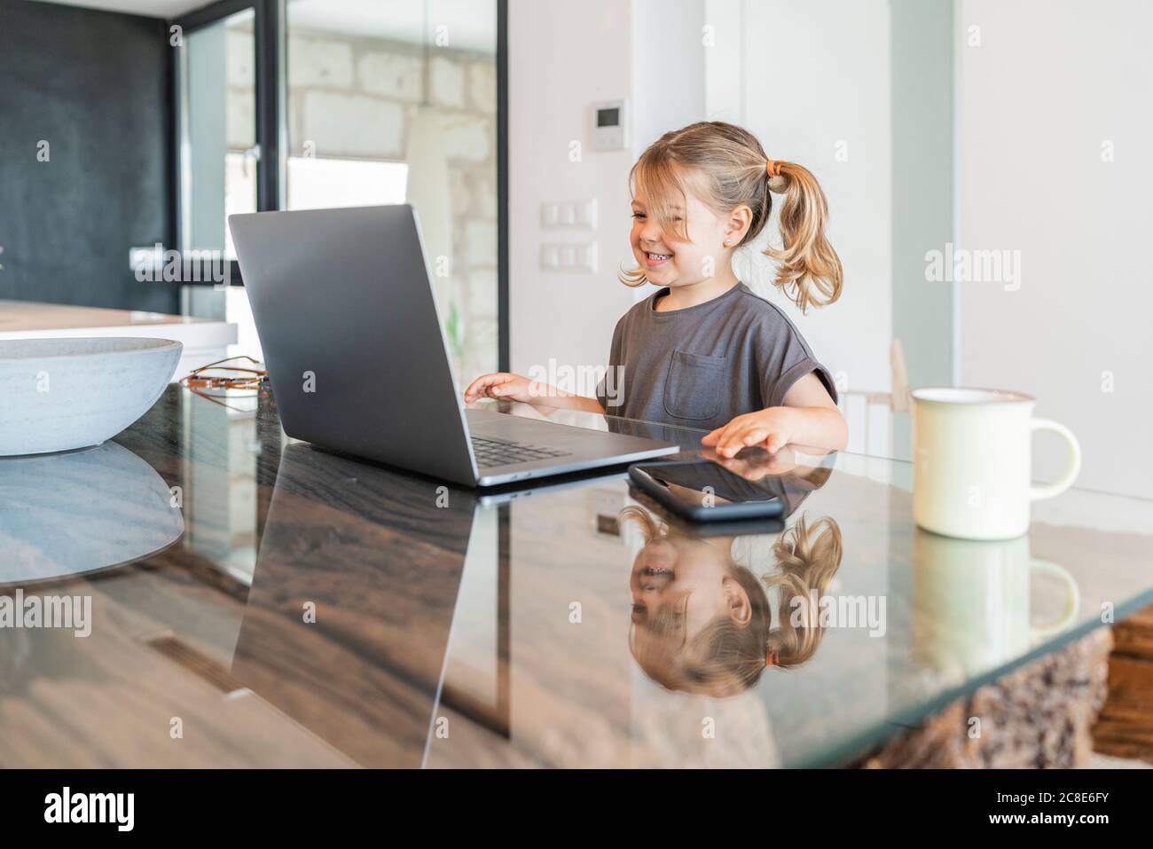 Sorridente ragazza carina che studia su un computer portatile a casa Foto Stock