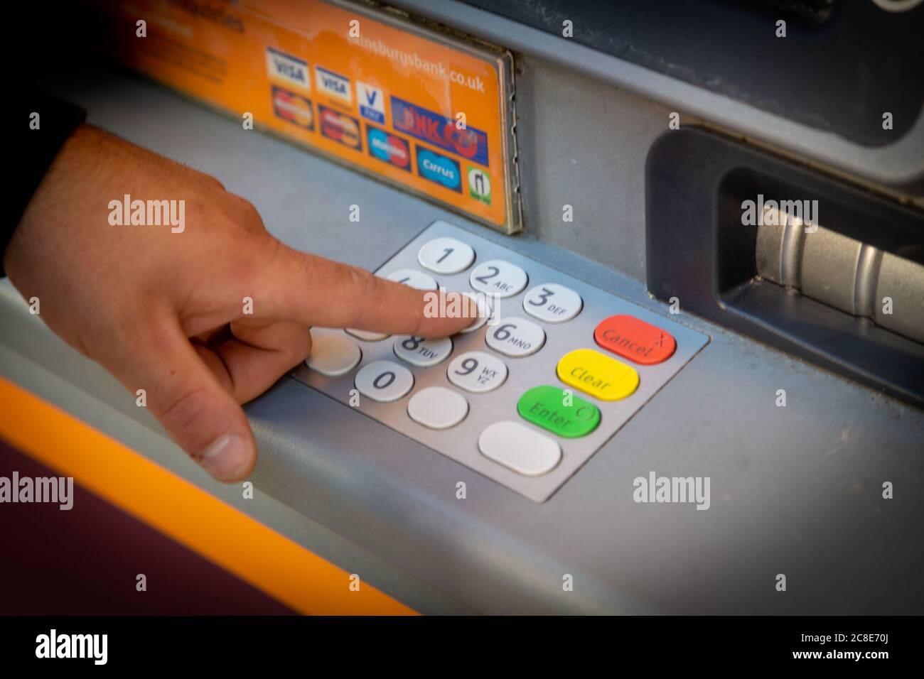 Un dito che preme i pulsanti numerati per immettere il numero PIN su una cassa o un bancomat Foto Stock
