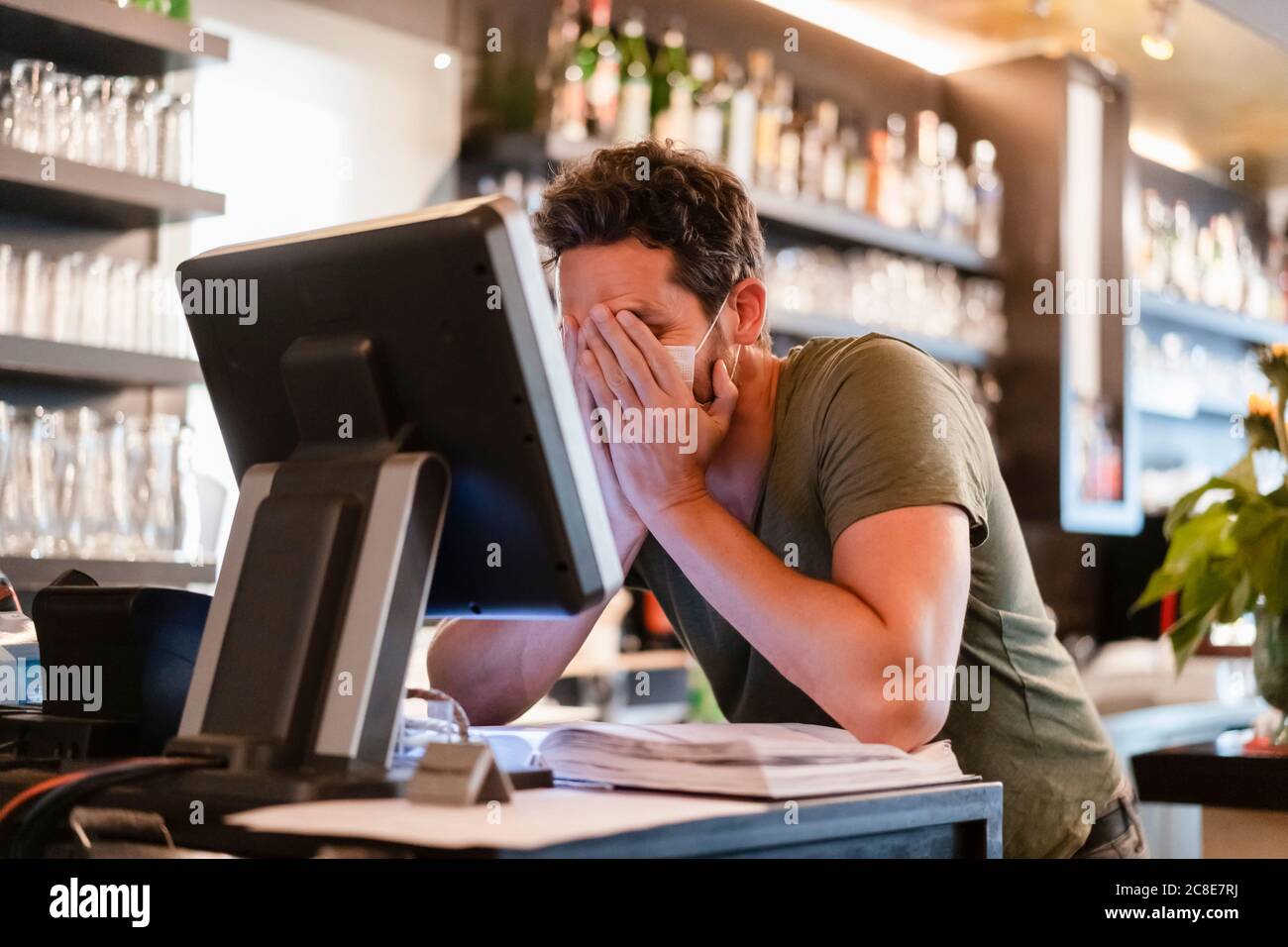 Responsabile del ristorante con le mani in faccia durante la crisi della corona Foto Stock