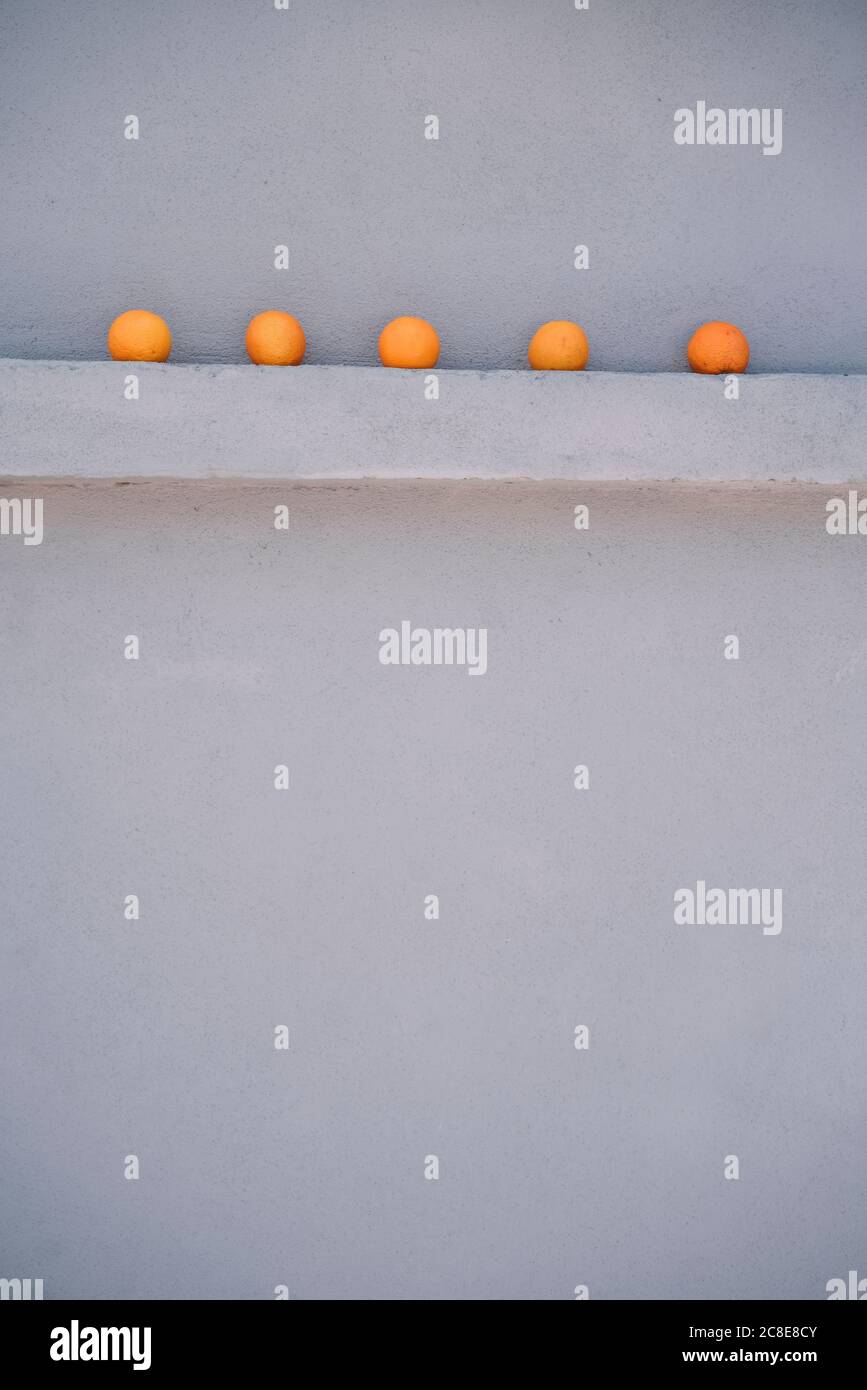 Cinque arance su uno sperone grigio Foto Stock