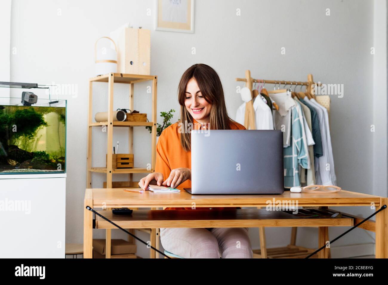 Donna stilista di moda che lavora a casa seduto alla scrivania con computer portatile Foto Stock