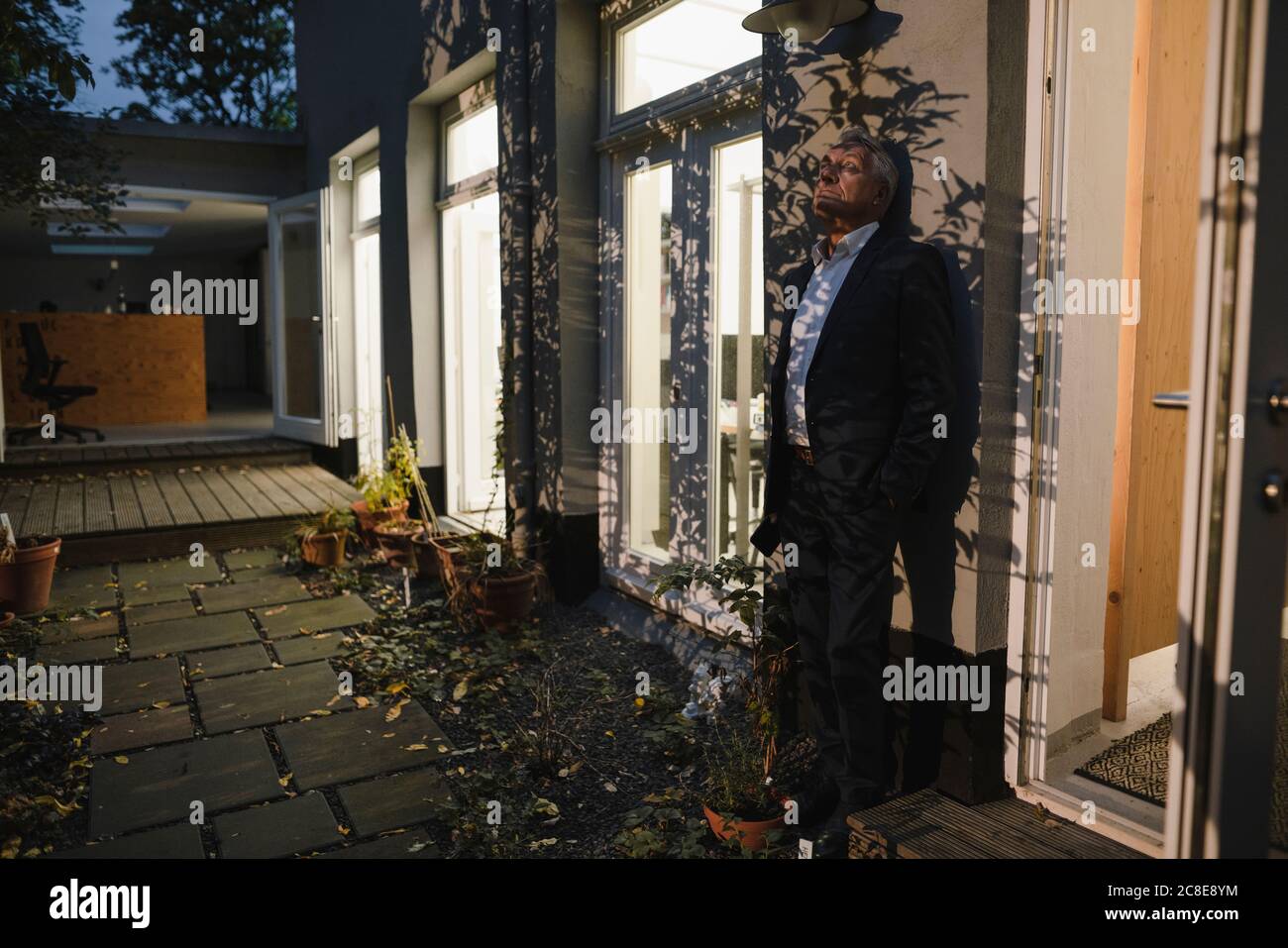 Uomo d'affari anziano che lavora straordinario, prendendo una pausa nel cortile del suo ufficio Foto Stock