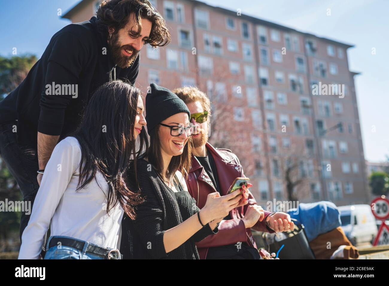 Amici che cercano uno smartphone utilizzato da una giovane donna in città Foto Stock