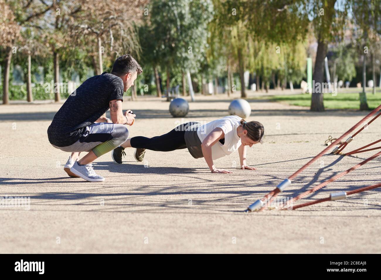 Donna durante il lavoro con allenatore nel parco Foto Stock