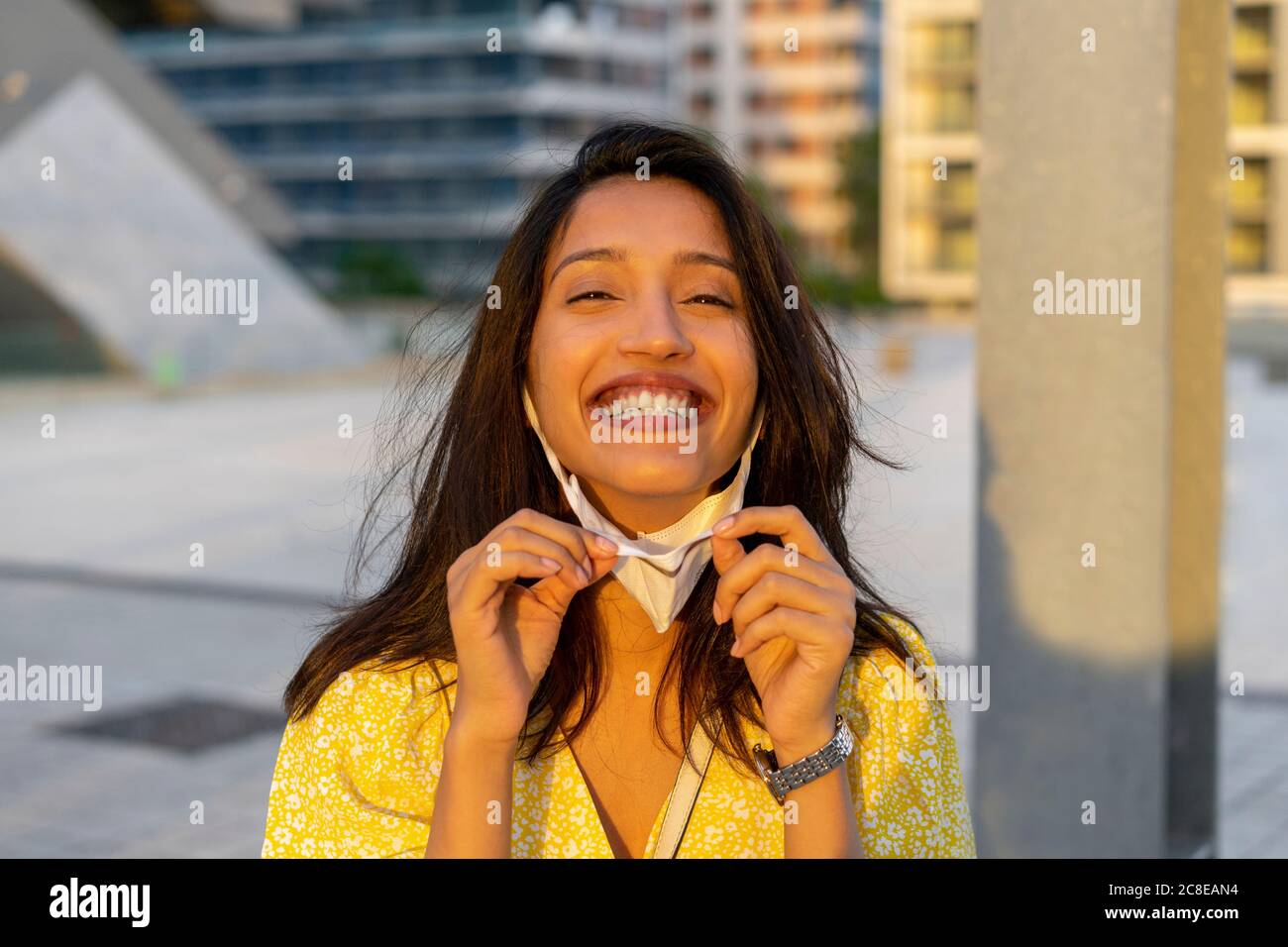 Giovane donna allegra con maschera facciale in città Foto Stock