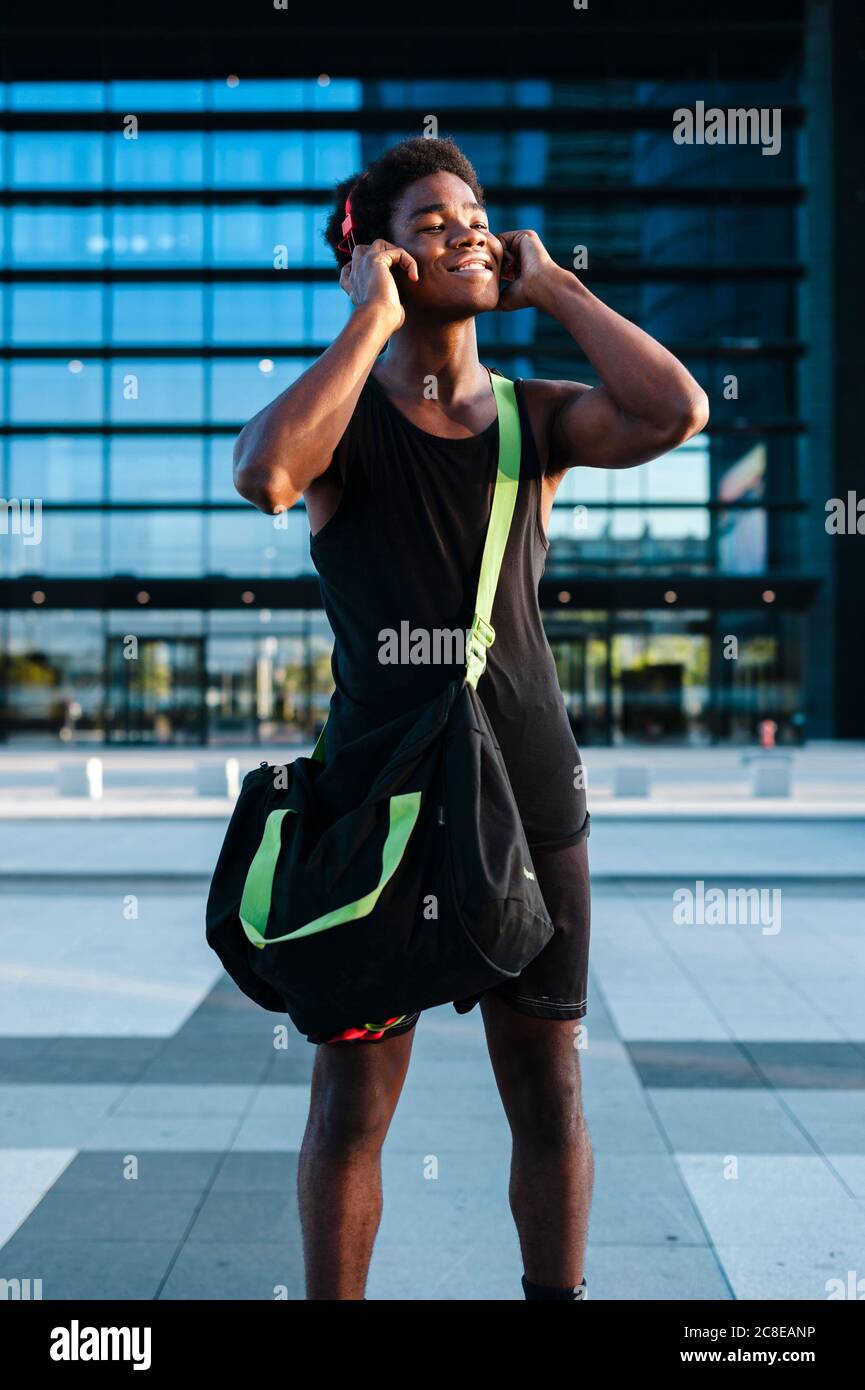 Un giovane sorridente con le cuffie che ascoltano la musica nel città Foto Stock