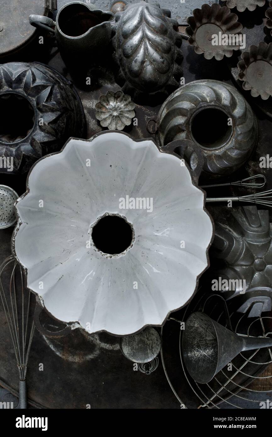 Collezione di vecchi utensili da cucina rustici tra cui teglie, teglia da forno, frusta e imbuto Foto Stock
