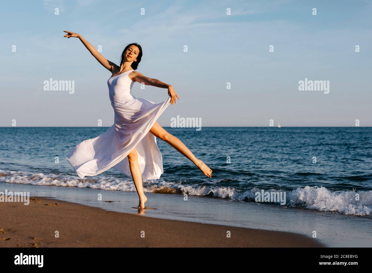 Ballerina in abito bianco danzante al mare Foto Stock