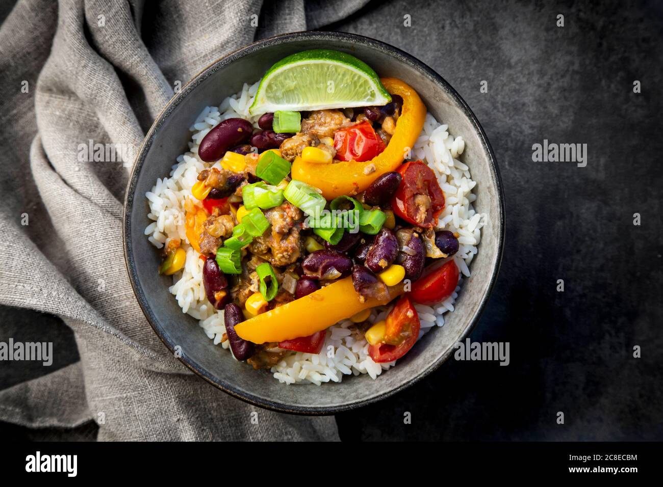 Ciotola di riso messicano con peperoni, tofu, fagioli, pomodori, mais, lime e scalione Foto Stock