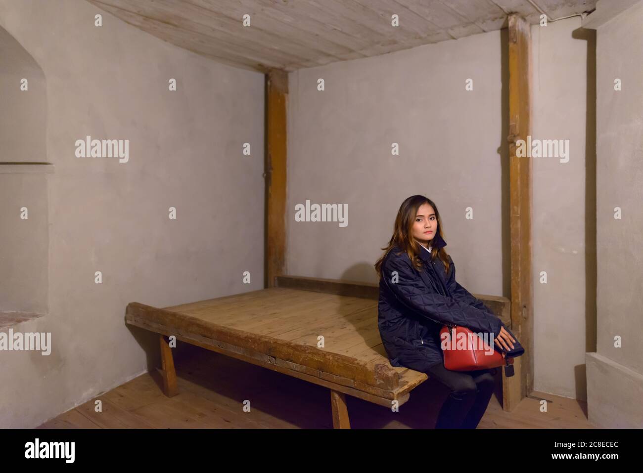 Giovane bella donna asiatica seduta su vecchio telaio di legno all'interno di edificio storico Foto Stock