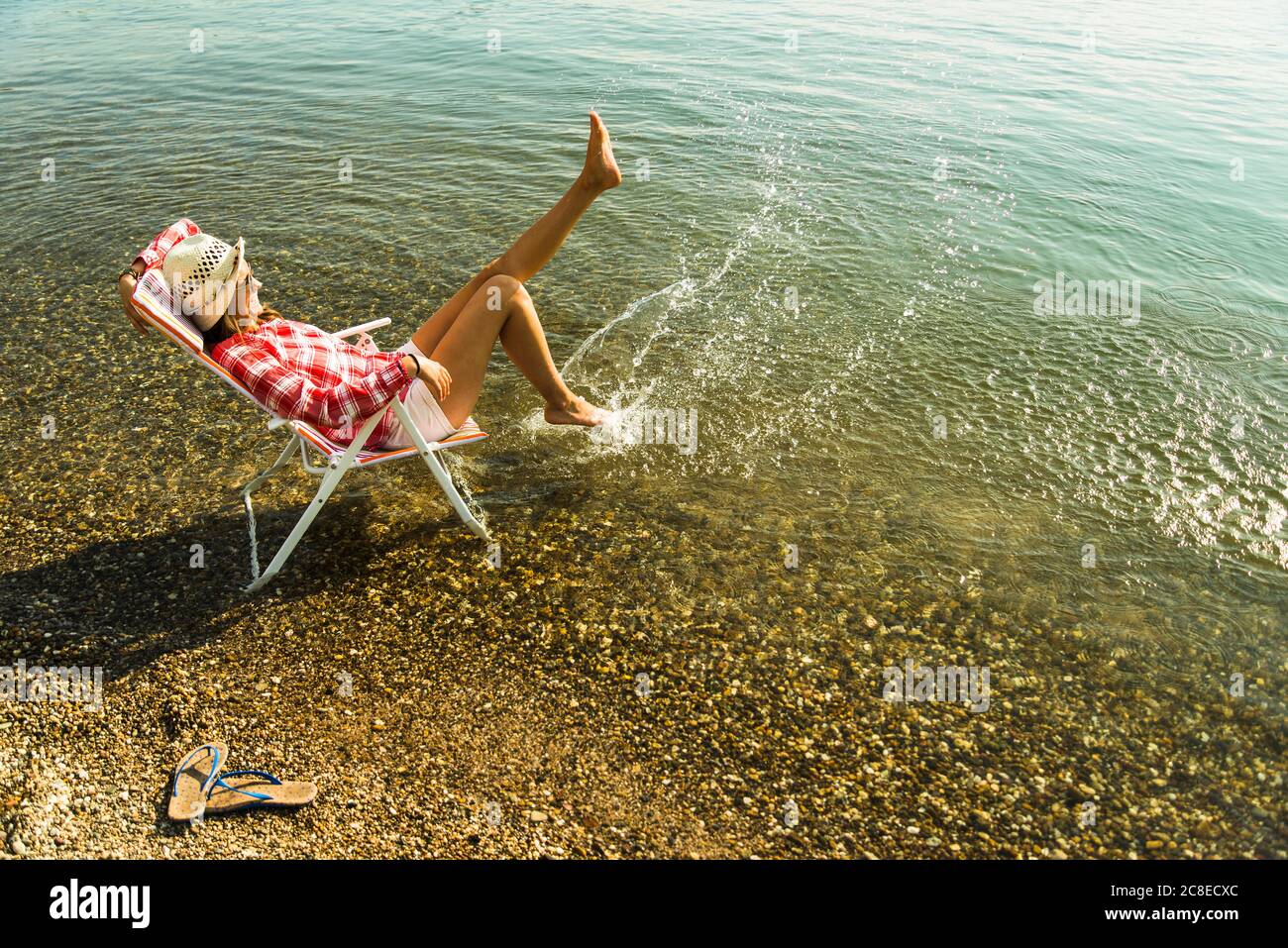 Giovane donna seduta sulla sedia a sdraio nel fiume schizzi con acqua Foto  stock - Alamy