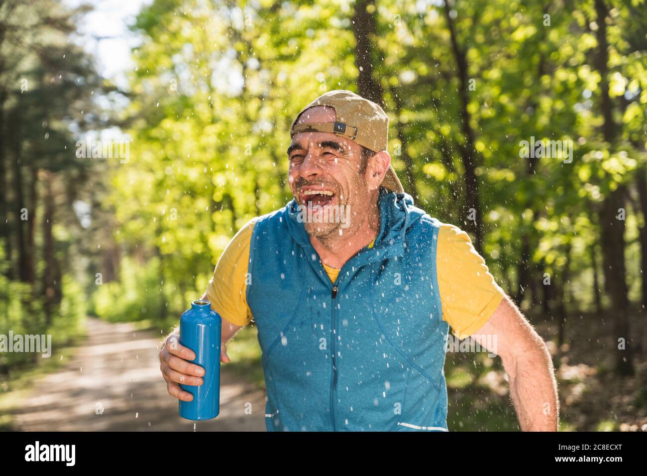 Uomo allegro che guarda via mentre in piedi tra gocce d'acqua a. parcheggio Foto Stock