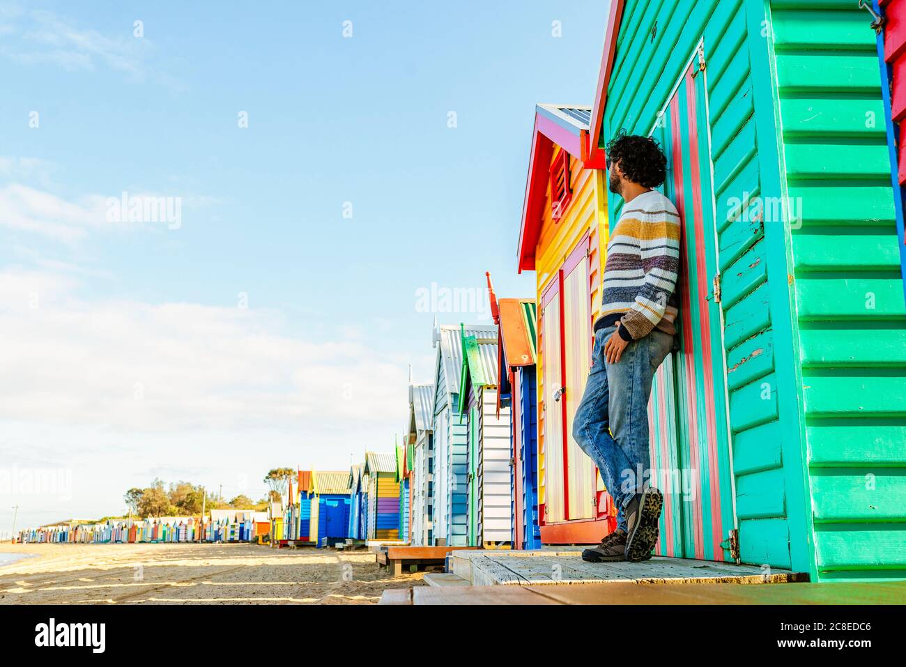 Uomo in piedi da cottage a Brighton Beach contro cielo, Melbourne, Australia Foto Stock