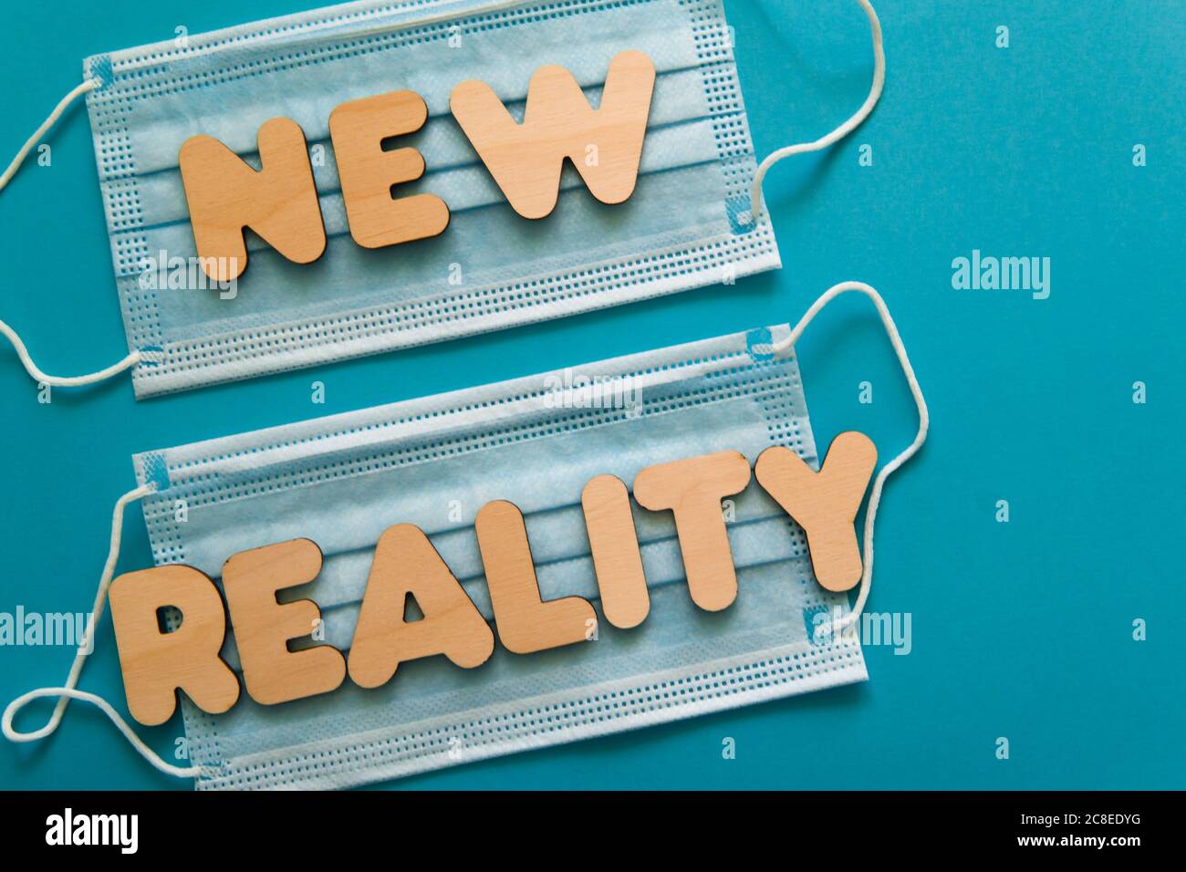 NUOVE parole DI REALTÀ sulle maschere facciali protettive su sfondo blu. Dopo covid-19 pandemie cambiamenti, nuova normale, indossare maschera viso in concetto pubblico. Foto Stock