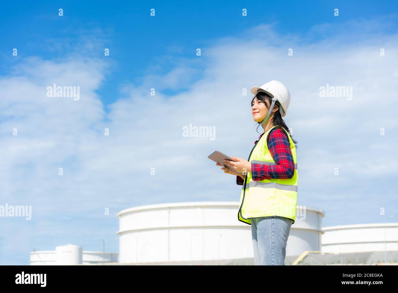 Donna asiatica ingegnere petrolchimico che lavora con tablet digitale all'interno di petrolio e gas raffineria stabilimento di fabbrica di notte per la sicurezza degli ispettori qualità Foto Stock