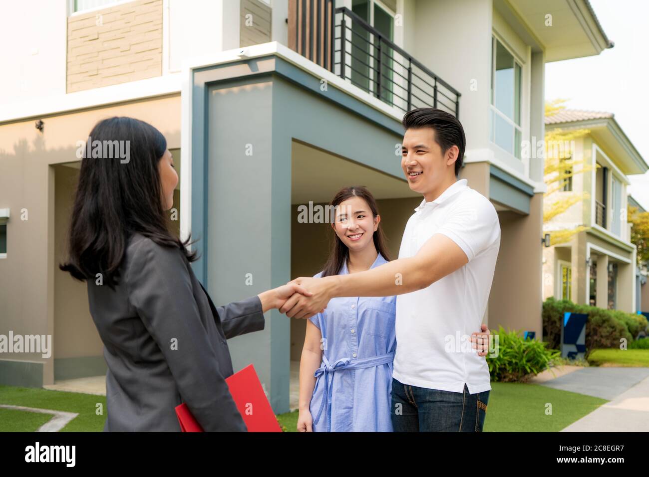 Felice coppia asiatica alla ricerca della loro nuova casa e agitare le mani con broker immobiliare dopo un accordo. Giovane coppia handshaking agente immobiliare dopo Foto Stock