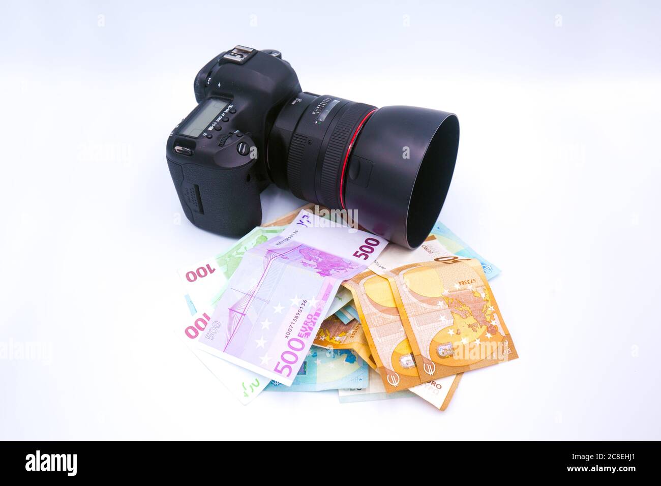 Fotocamera reflex digitale su denaro europeo in euro isolato su sfondo bianco. Fare soldi per la fotografia. Concetto di business di reddito dei fotografi Foto Stock
