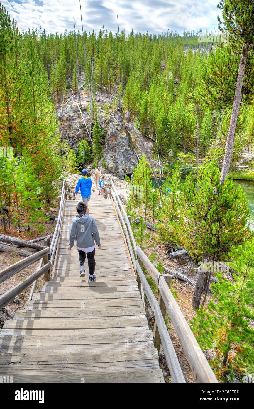 Wyoming, USA - 24 agosto 2019: I visitatori camminano lungo le scale di legno verso il fiume Firehole nel parco nazionale di Yellowstone, Wyoming, USA. Il fiume scorre Th Foto Stock