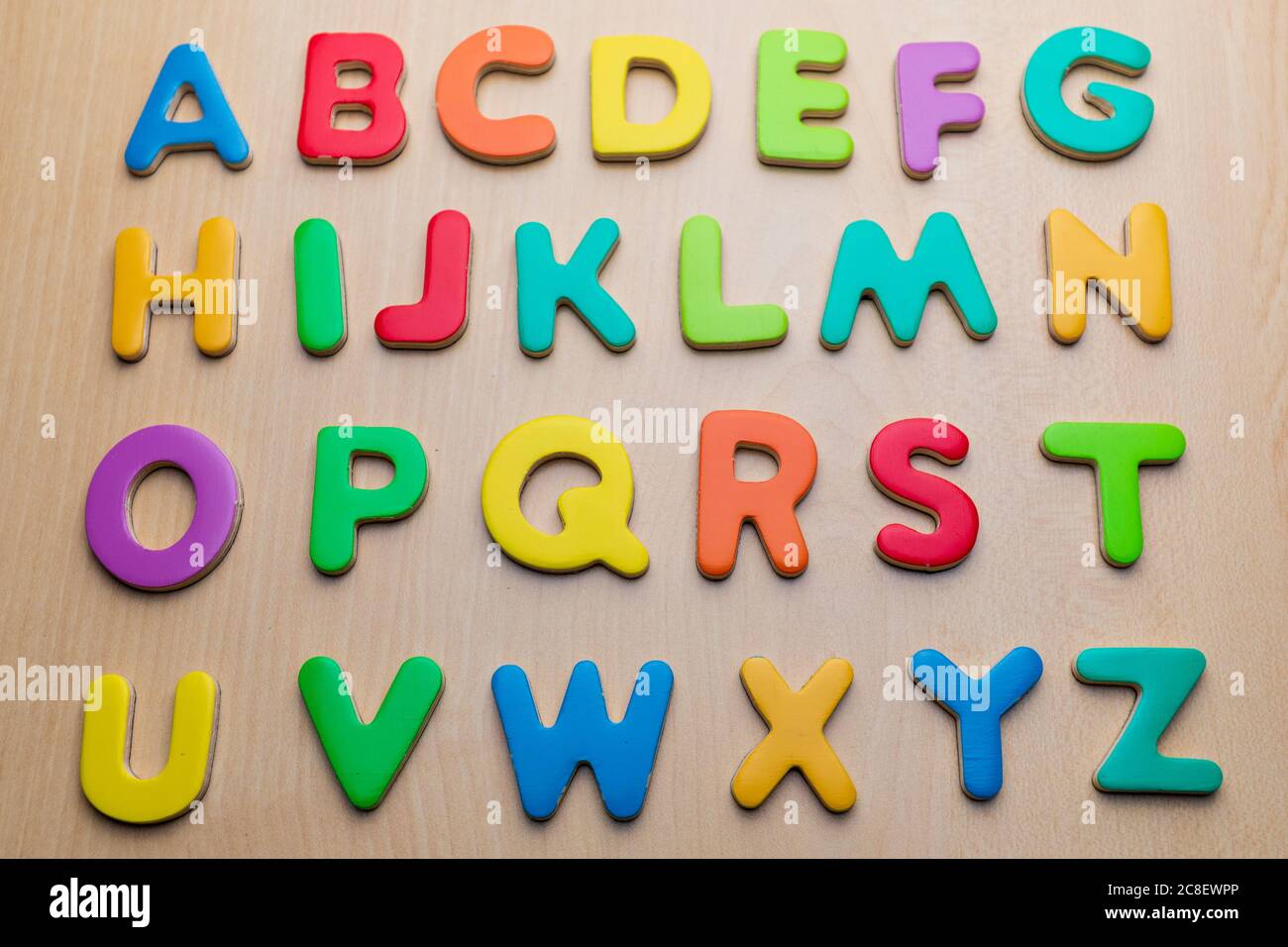 Lettere colorate su sfondo in legno, ordine alfabetico, vista dall'alto Foto Stock