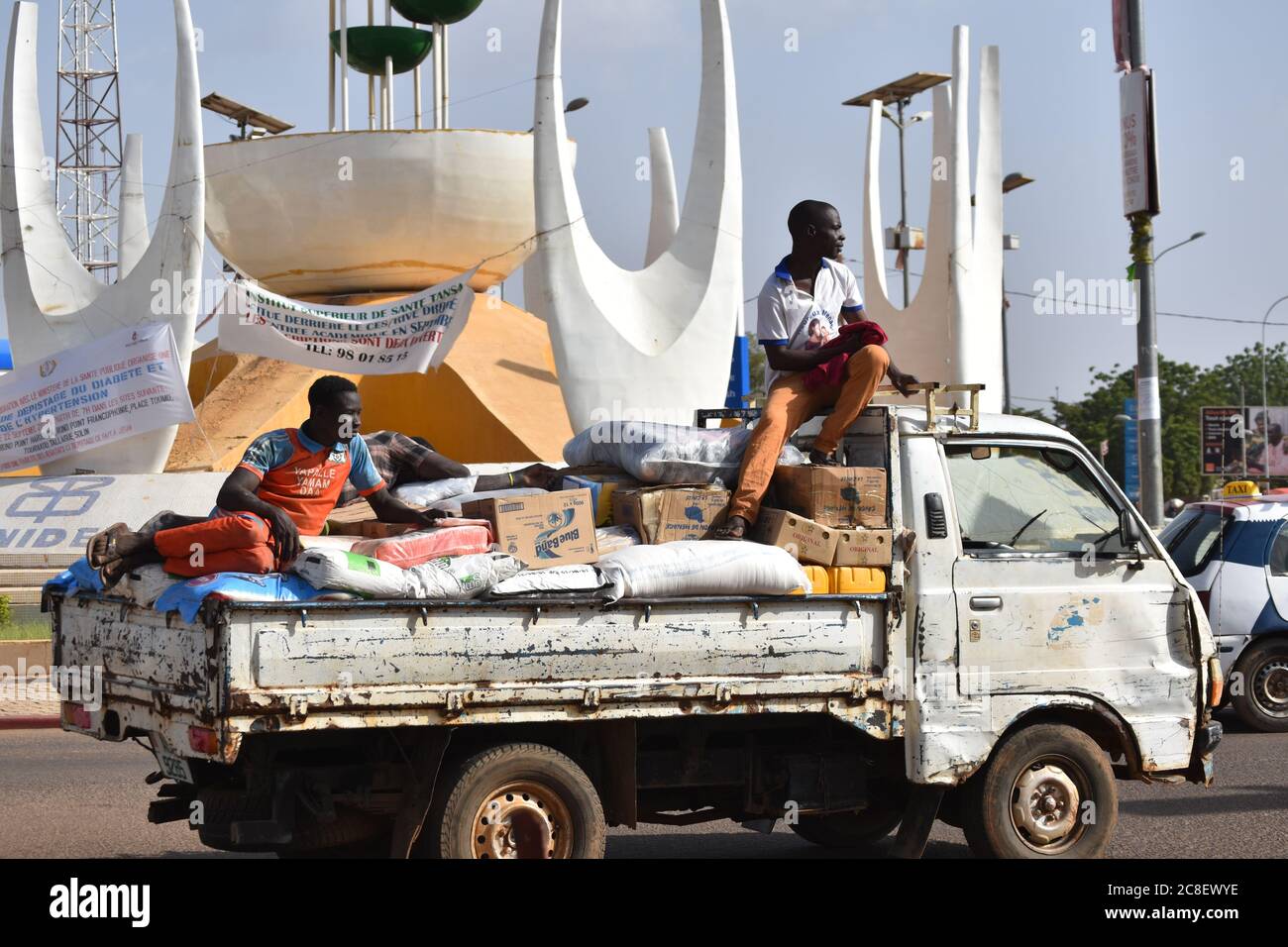 Due lavoratori siedono sopra il carico di un camion di consegna a Niamey, Niger. Foto Stock