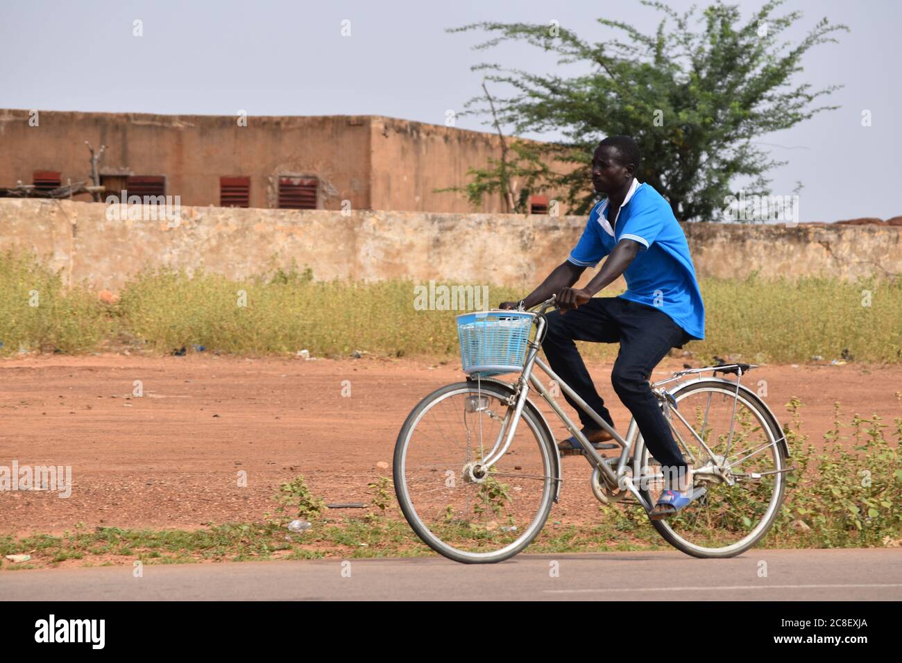 Un uomo che cavalcava la sua bicicletta sulle spalle di una strada del villaggio in Niger, Africa Foto Stock