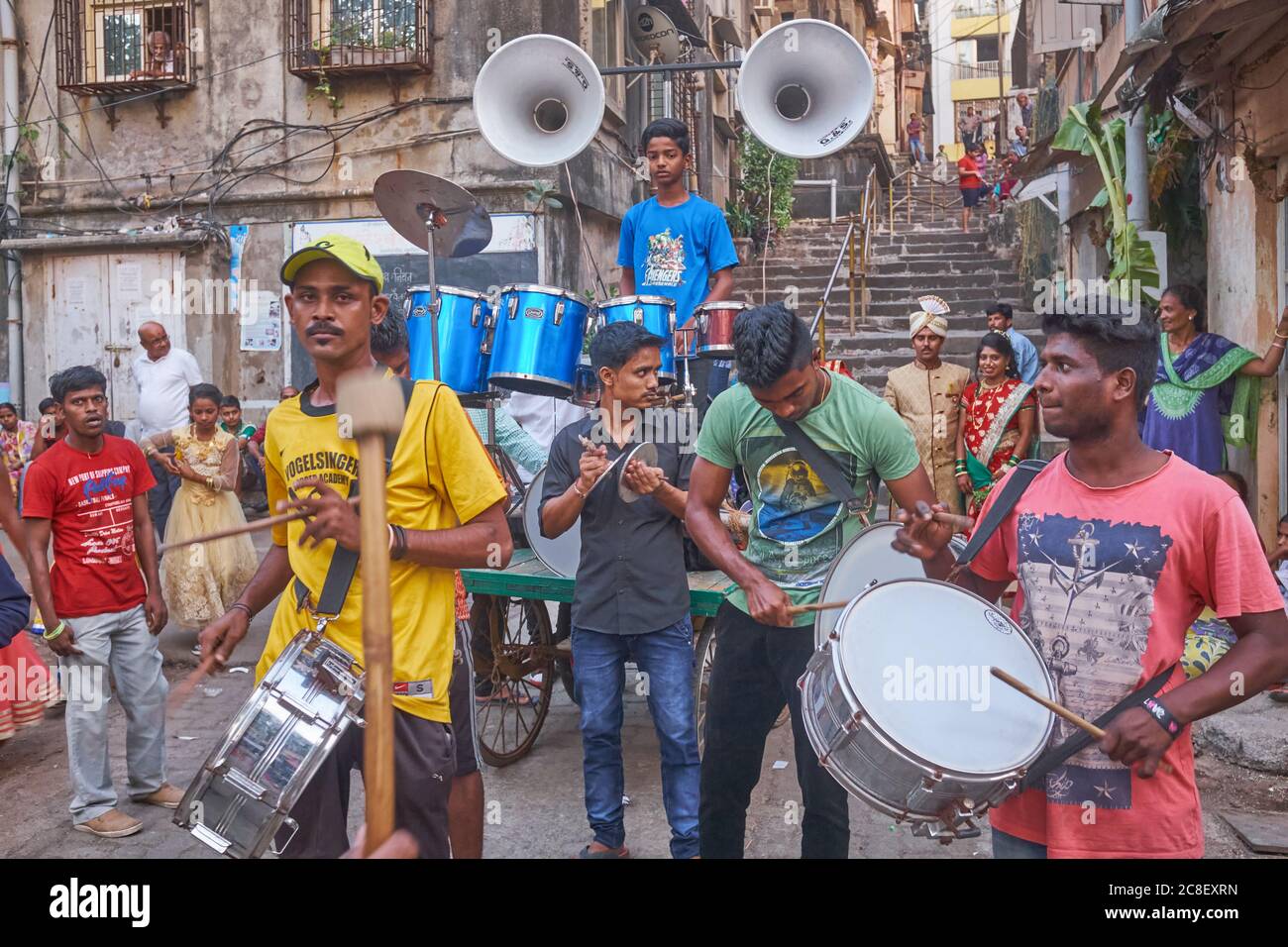 In un cortile a Mumbai, in India, una band nuziale sta giocando per una coppia appena sposata (sfondo a destra) in un insolitamente basso-chiave, basso-spese matrimonio indù Foto Stock