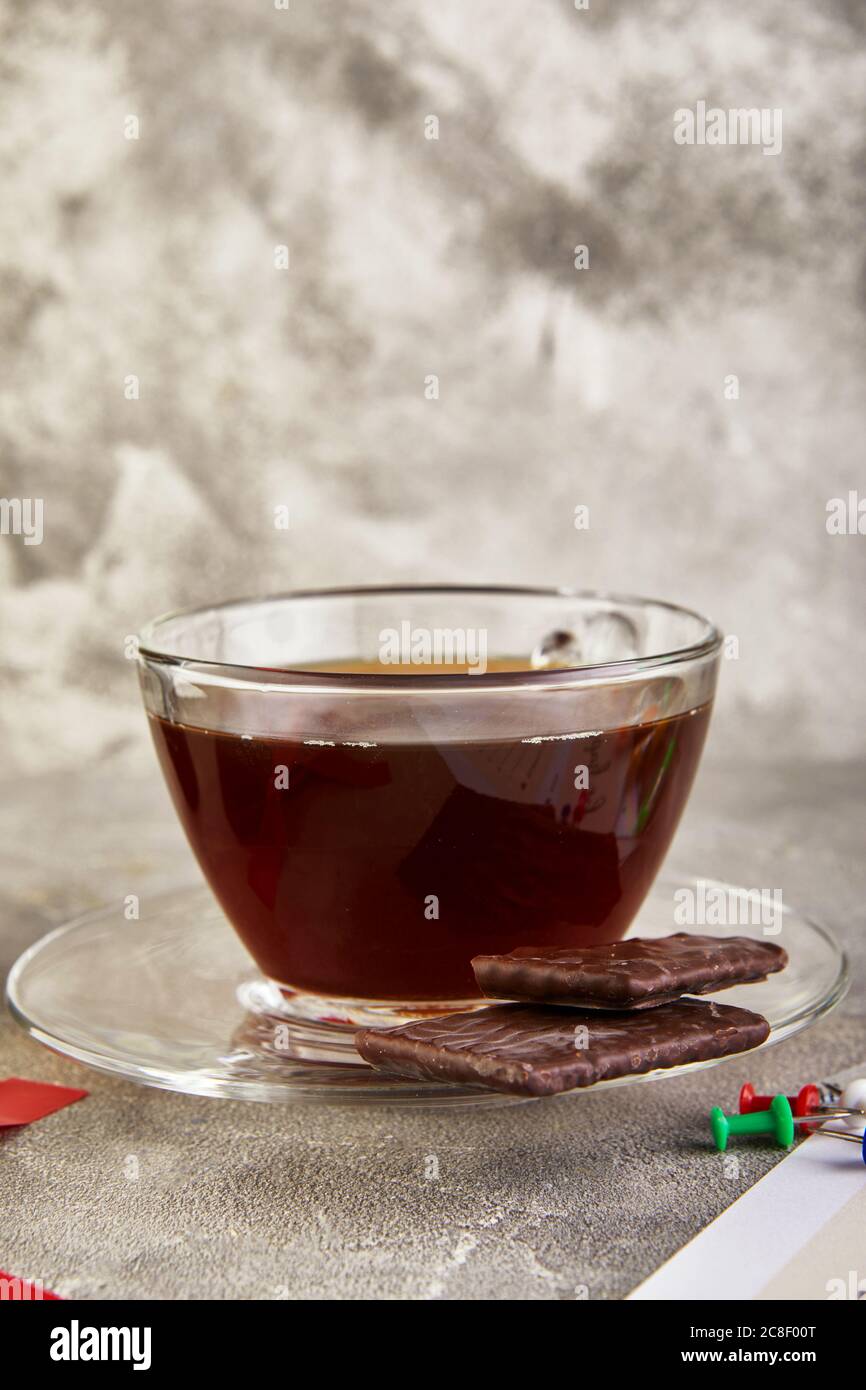 Una tazza di caffè con cioccolato e penne colorate, fogli di un diario con l'iscrizione su fondo grigio in cemento. Foto Stock