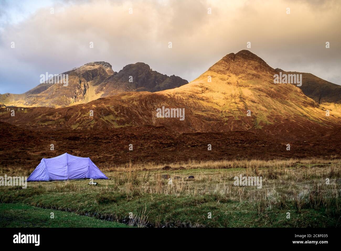 Tenda che si erge nella natura selvaggia dell'altopiano scozzese sull'isola del cielo durante l'alba. La catena montuosa nera dei cuillins Foto Stock