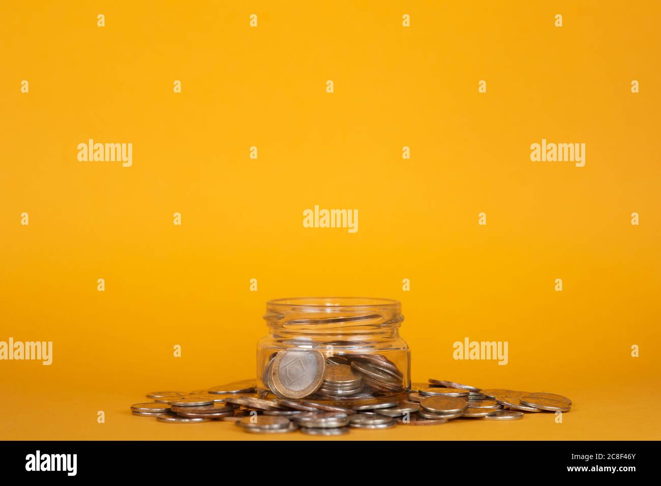 salva le finanze accumulandole. vaso di vetro su sfondo giallo Foto Stock