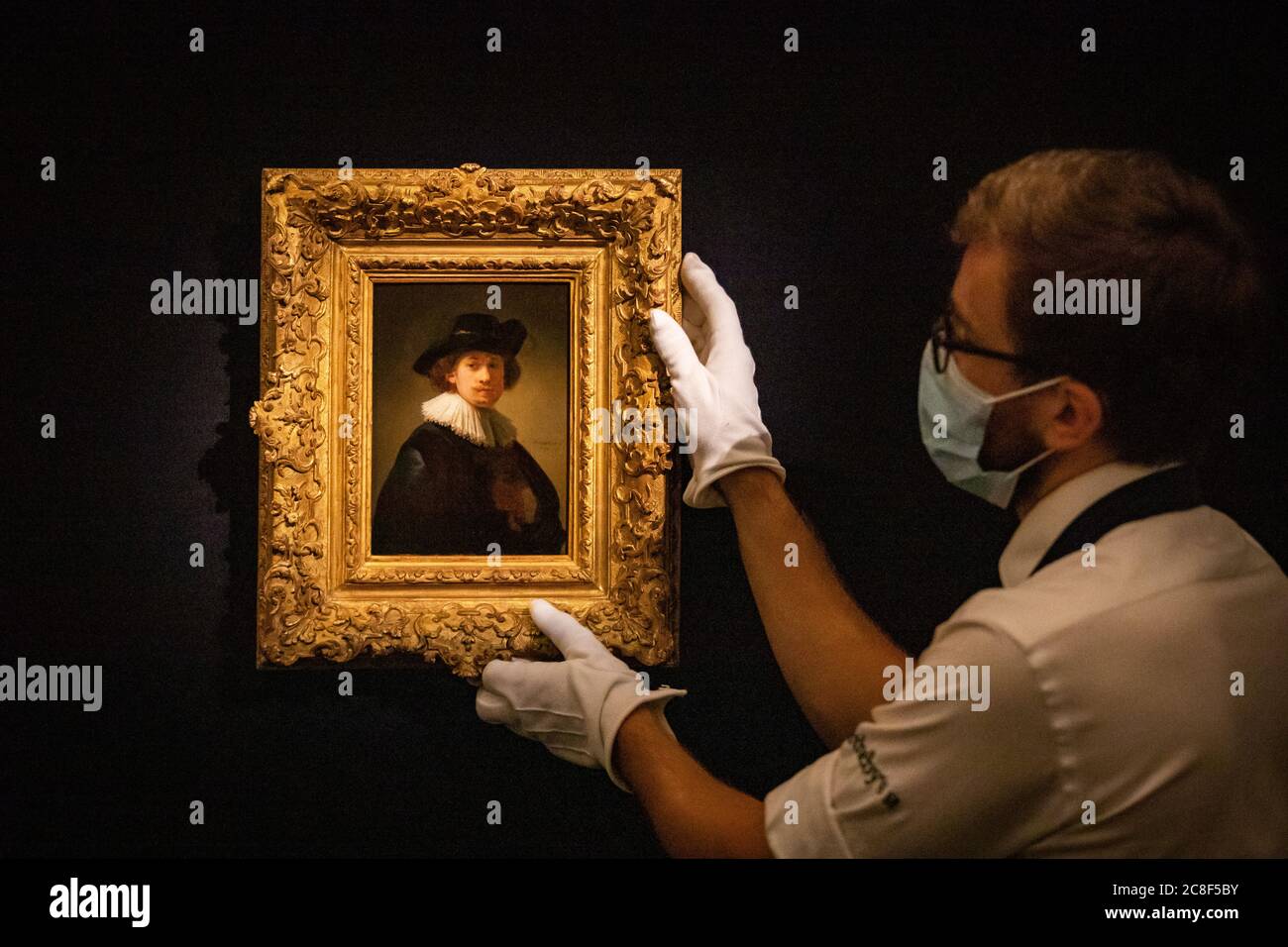 Assistenti di galleria davanti a Self-Portrait, con un ruff e cappello nero di Rembrandt, 1632, olio su pannello di quercia con una stima di 12-16 milioni di GBP durante un'anteprima stampa a Sotheby's a Londra in vista della loro vendita 'da Rembrandt a Richter' il 28 luglio. Foto Stock